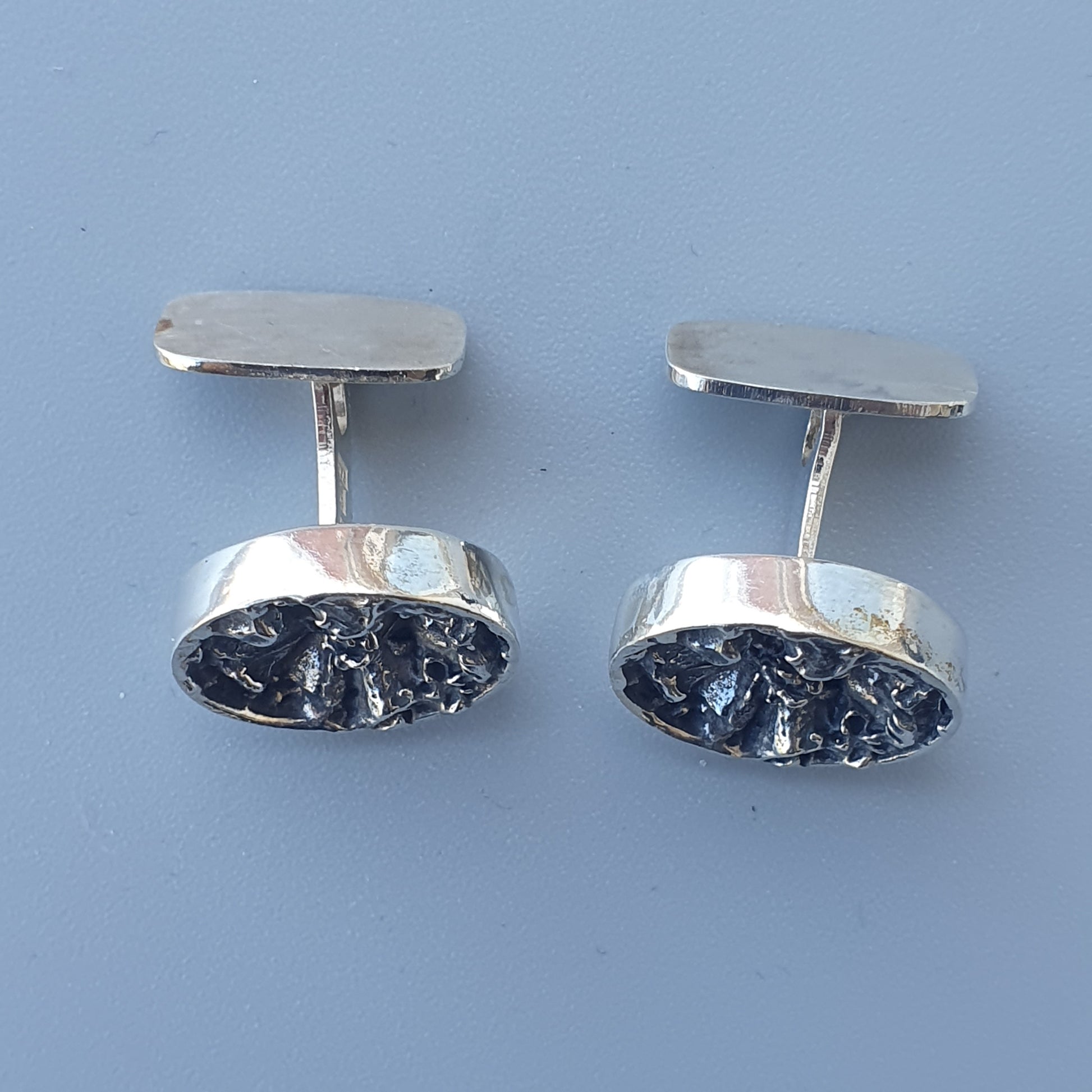 Pair of silver cufflinks with dark textured centers.