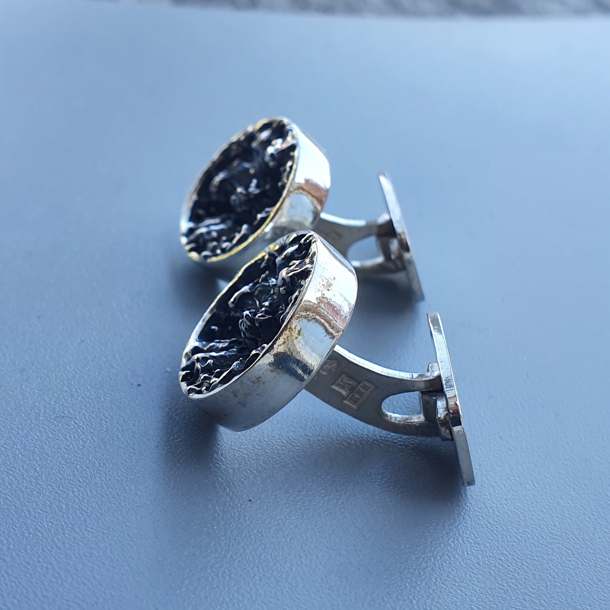 Pair of silver cufflinks with dark, textured inlays.