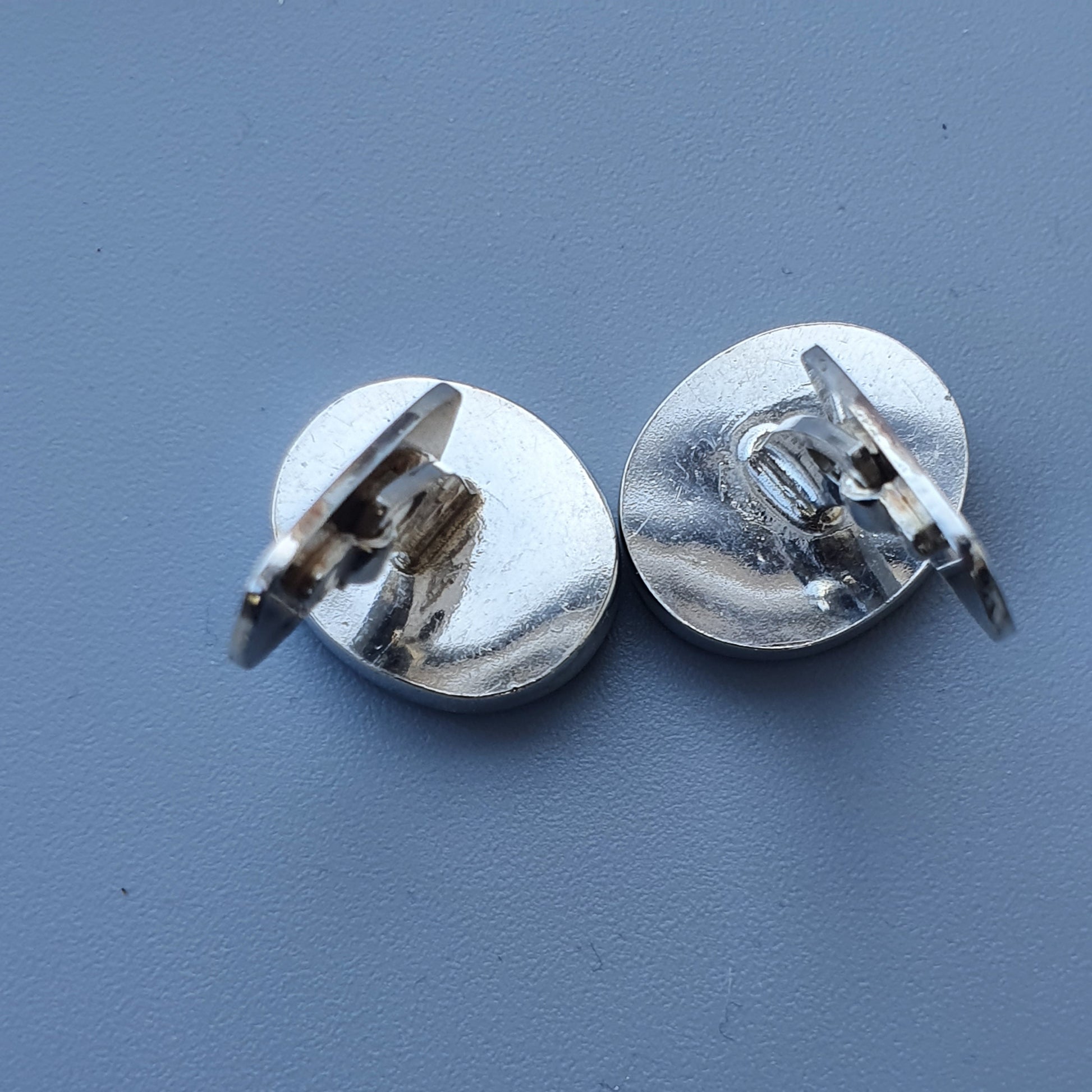 Pair of round, silver-colored clip-on earrings.