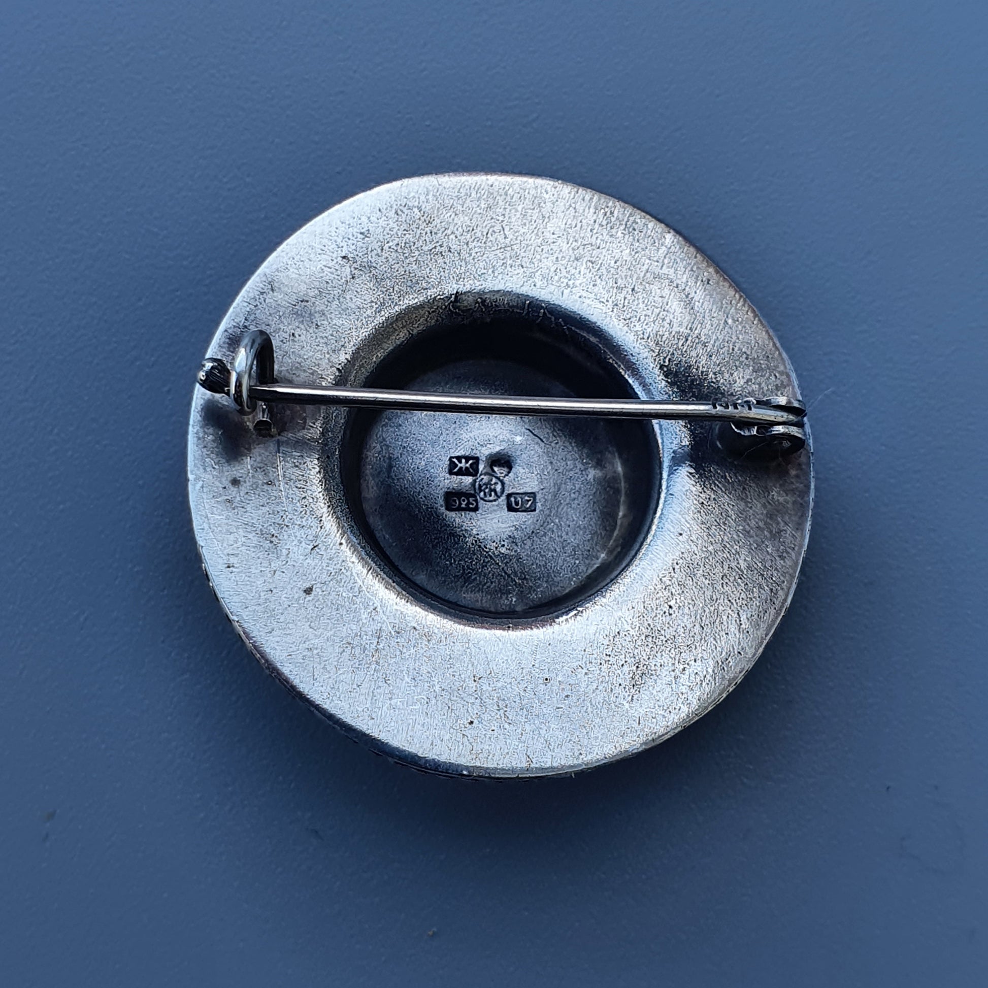 Circular metal ashtray with a cigarette resting across it.