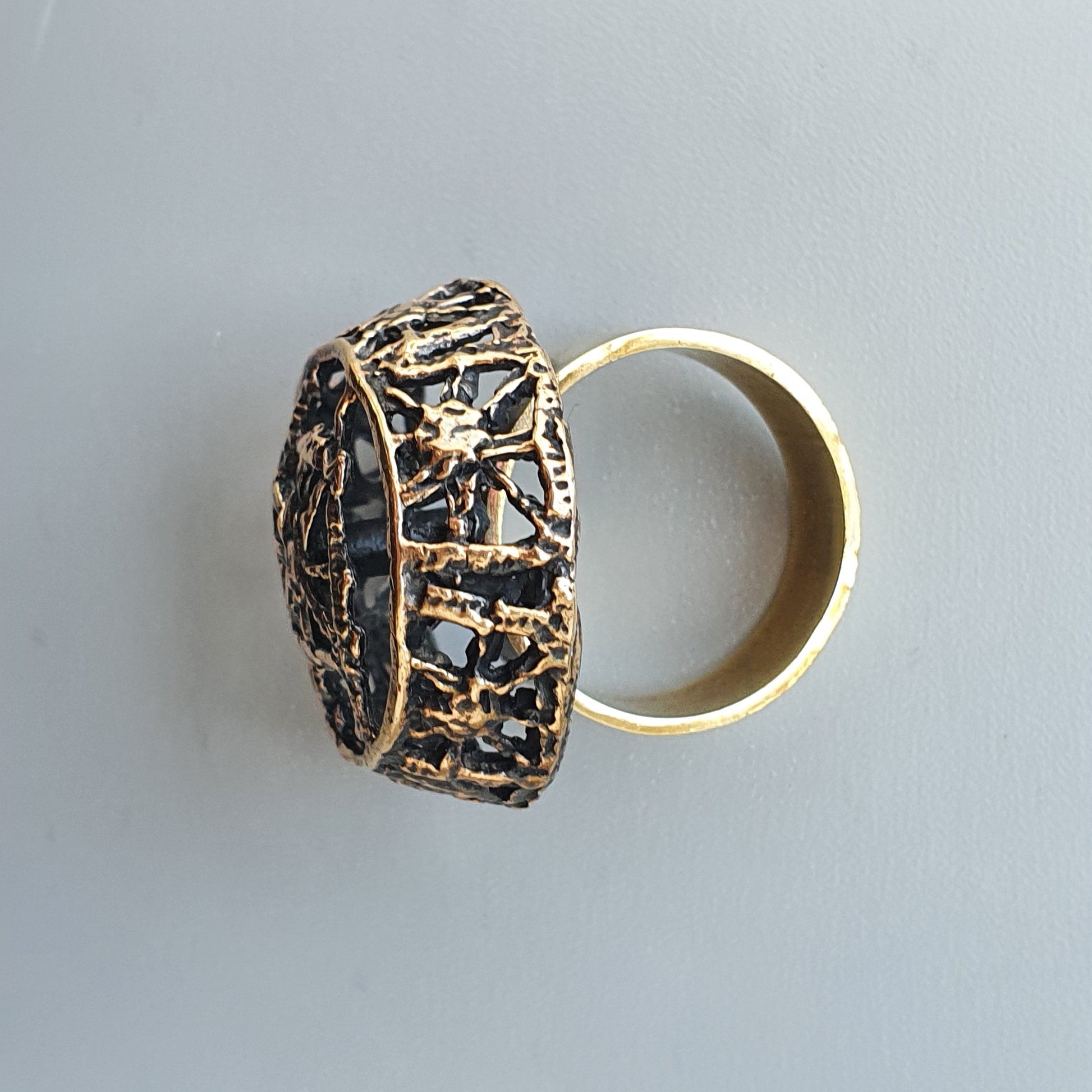 Ornate gold ring with an intricate, dome-shaped top featuring a textured, openwork design.