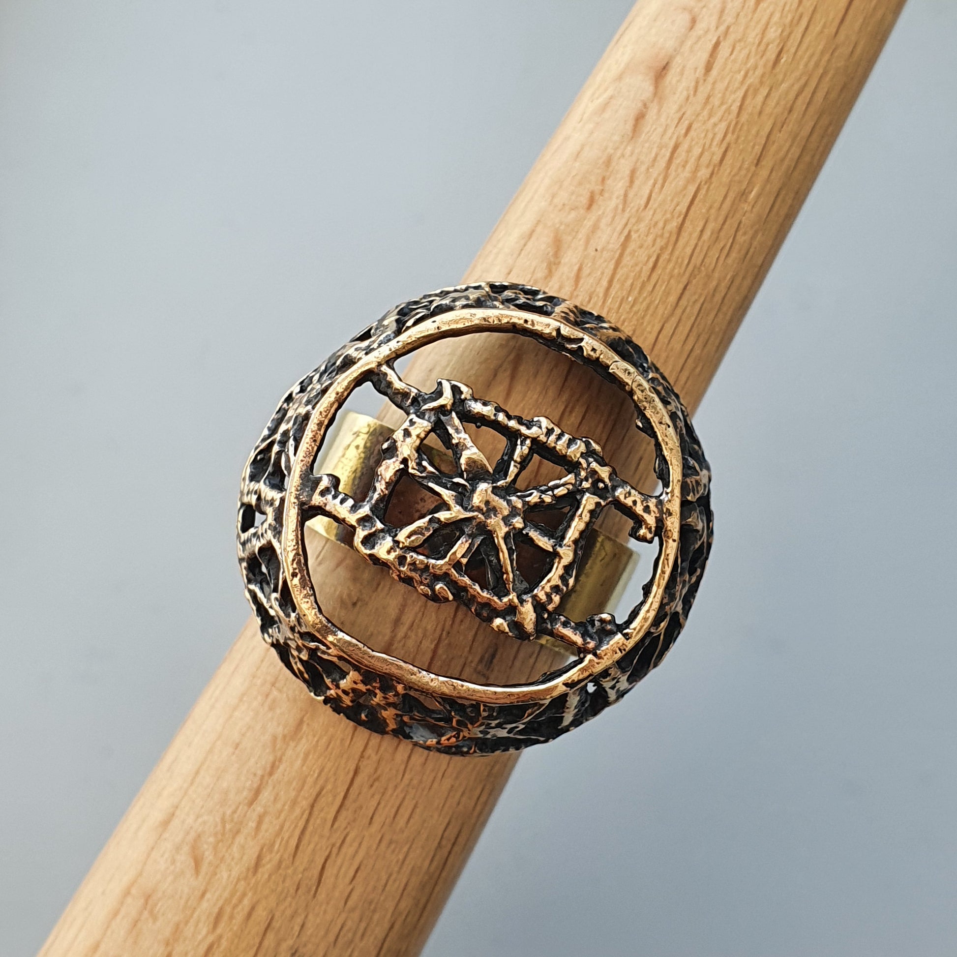 Ornate metal ring with an intricate geometric design on a wooden surface.