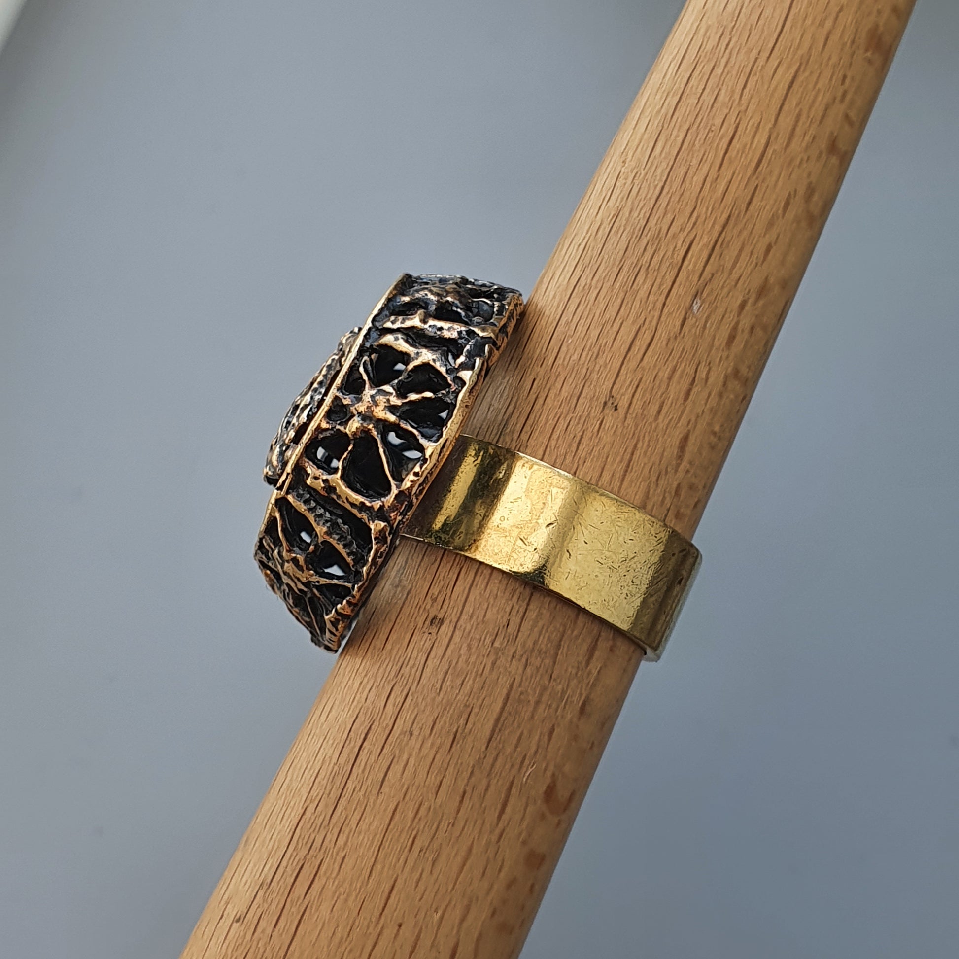 Ornate gold ring with intricate filigree design alongside a plain gold band.