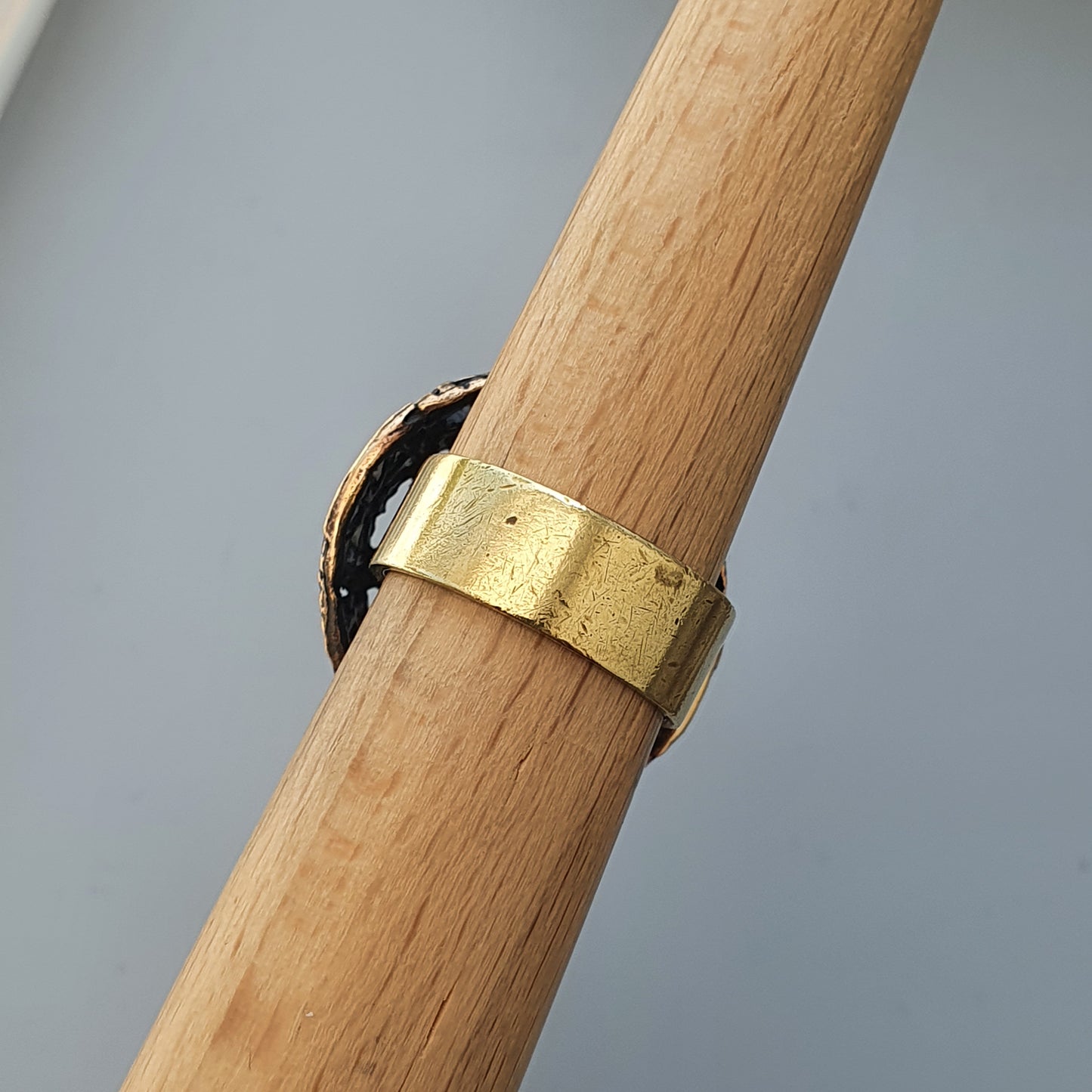 Gold ring wrapped around a wooden dowel or rod.