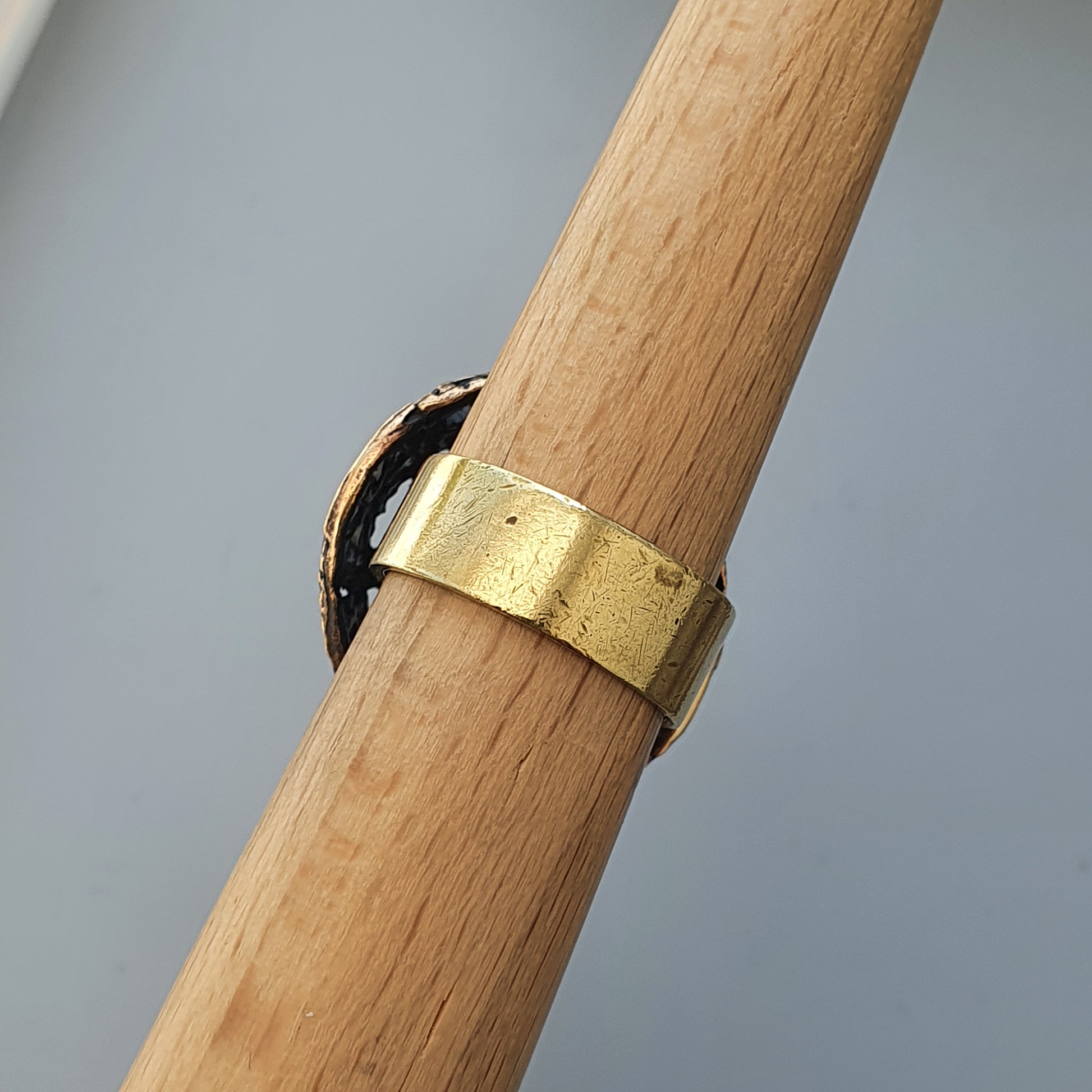 Gold ring wrapped around a wooden dowel or rod.