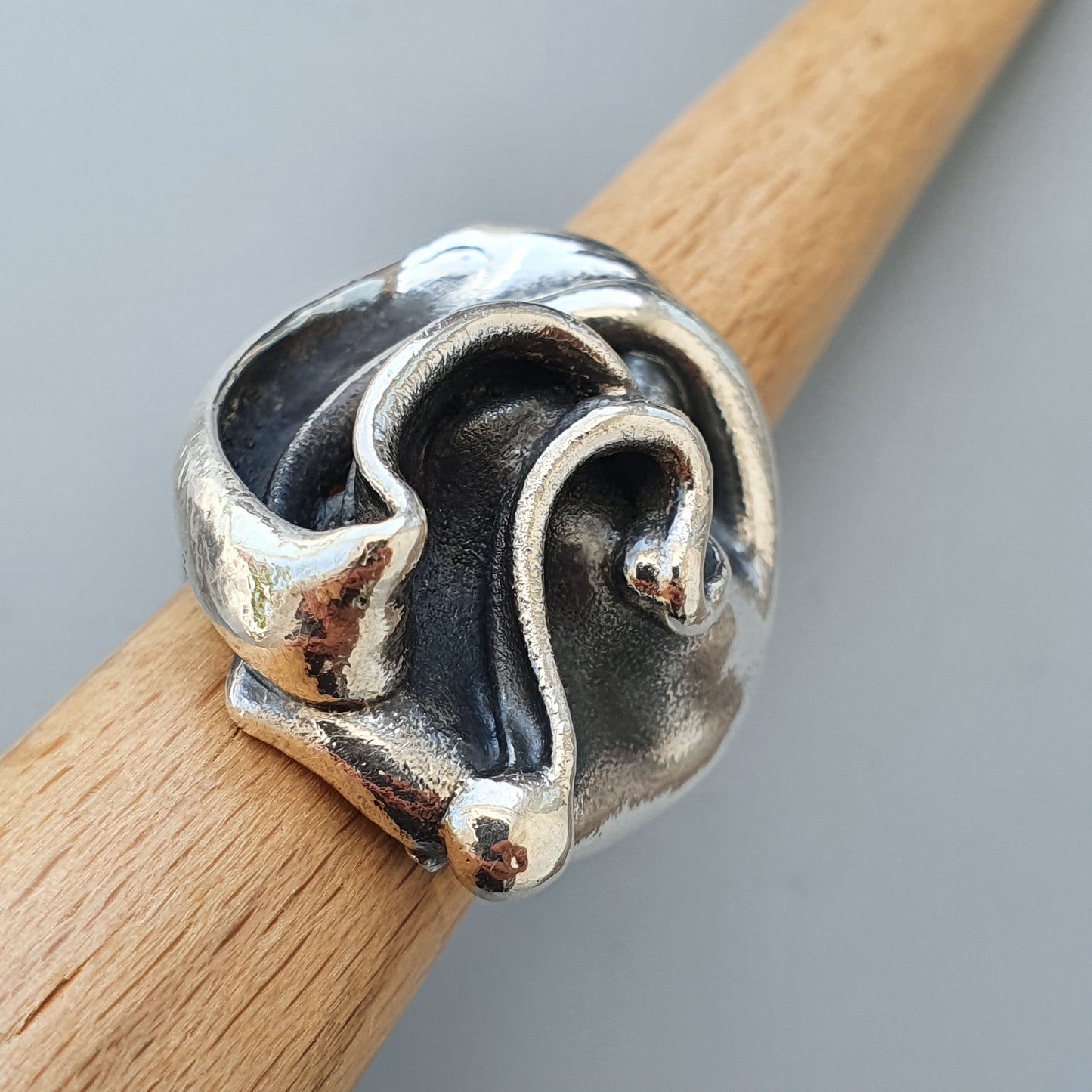 Unique silver ring with an abstract, organic design resembling flowing shapes or tendrils.