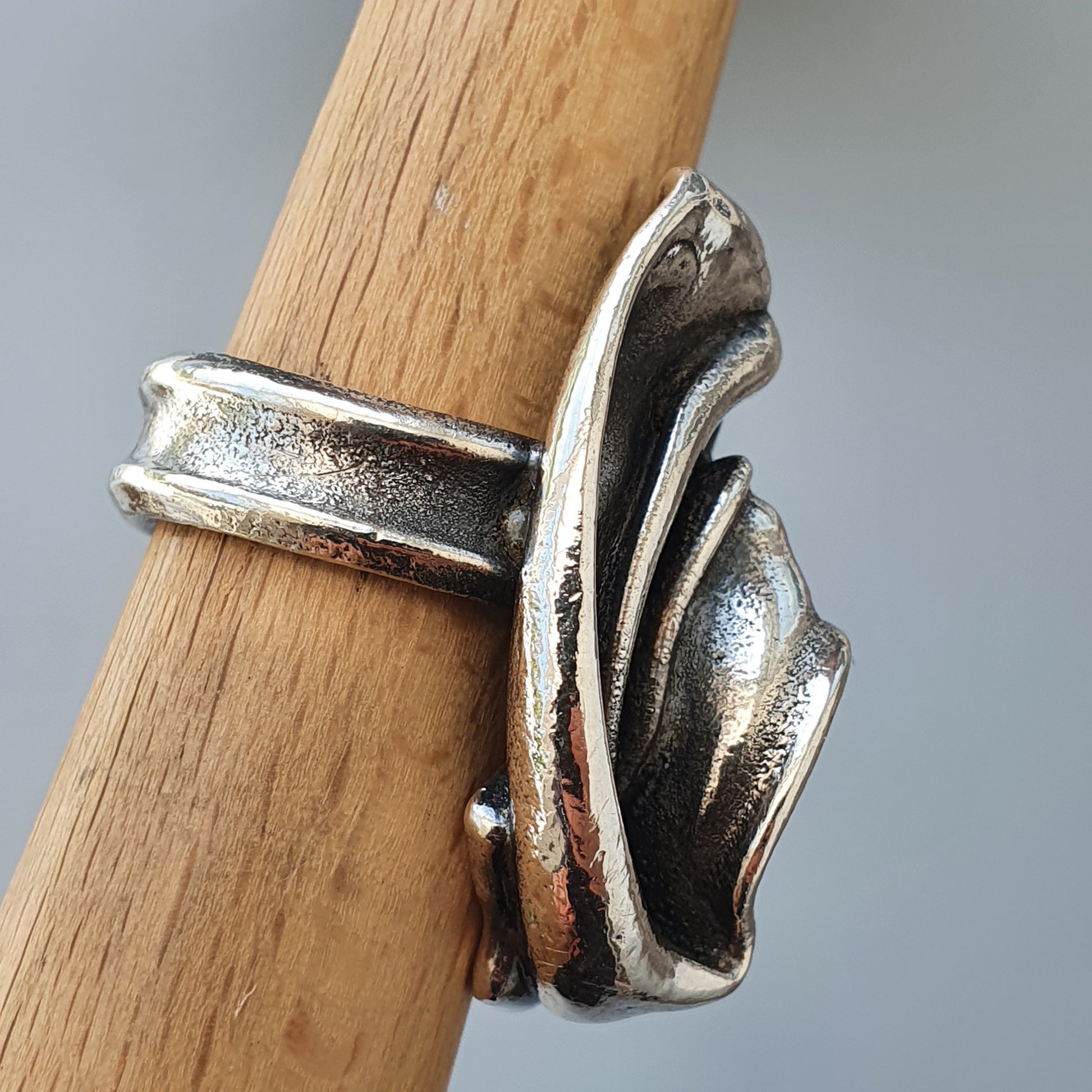 Silver ring with an abstract, flowing design resembling folded metal.