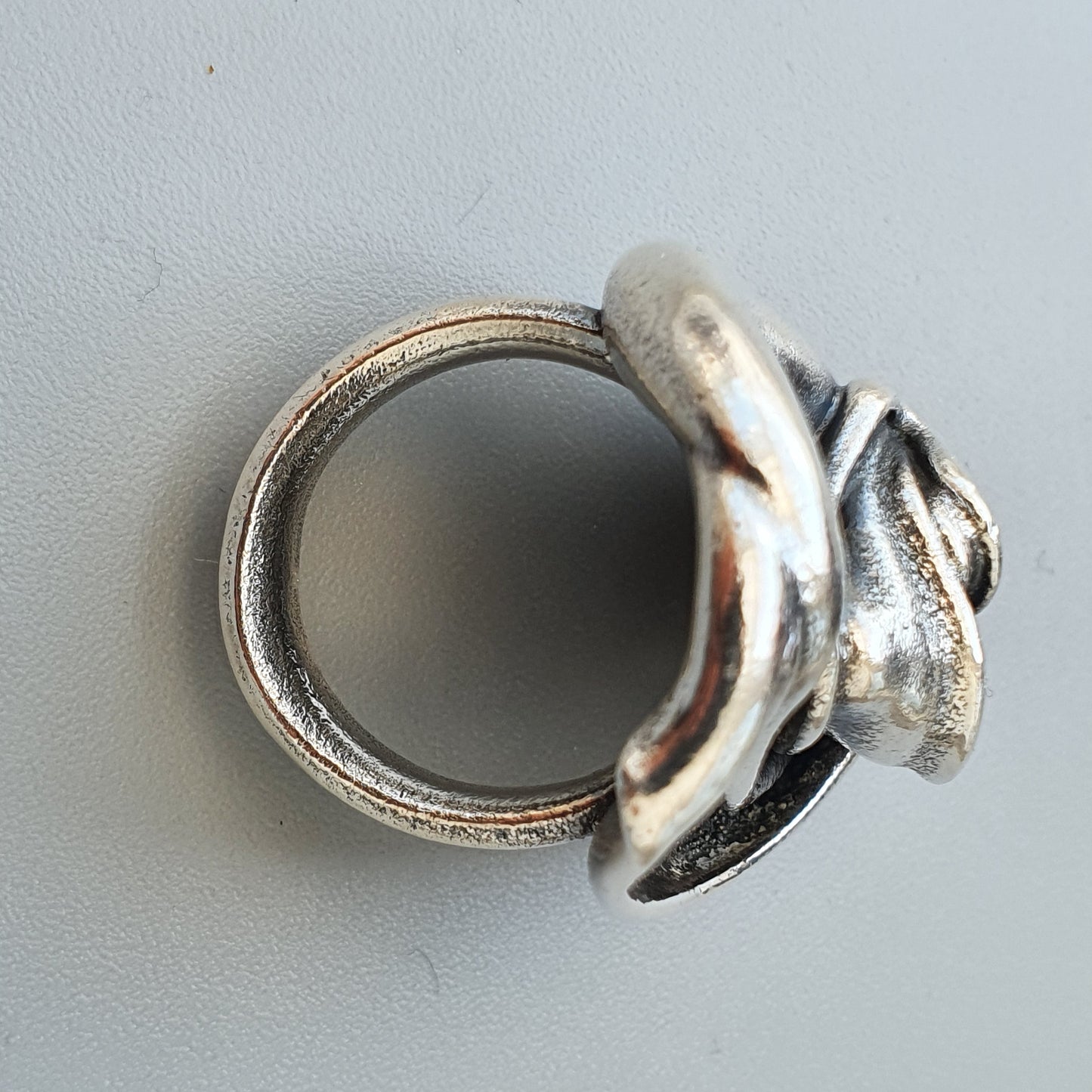 Silver ring with a distinctive dolphin-shaped design on top.