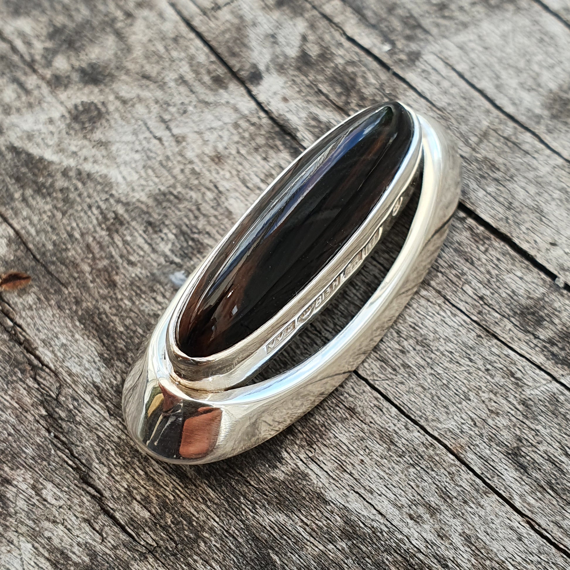 Sleek silver ring with an elongated black stone or gem inset.