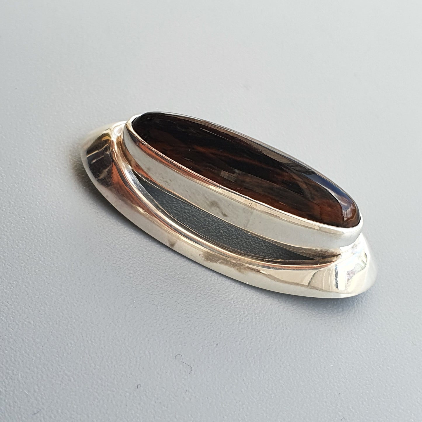 Silver ring with an oval dark brown gemstone.