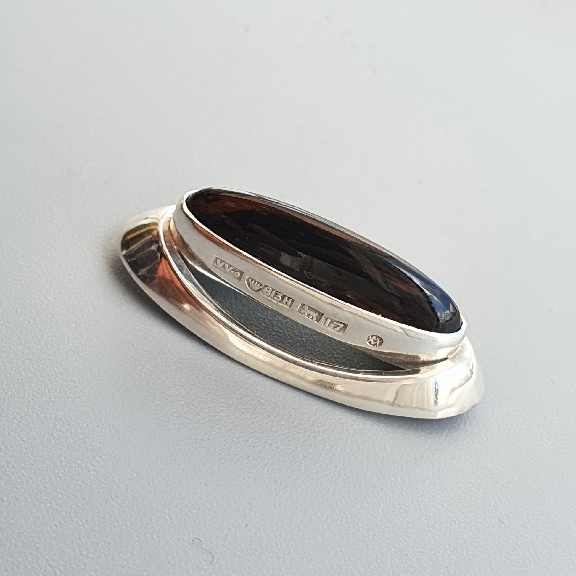 Silver ring with a dark center and engraved markings on the band.