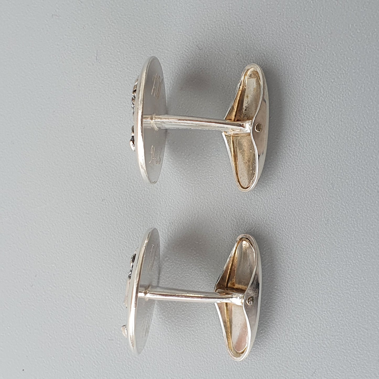 Pair of oval silver cufflinks with a connecting bar.