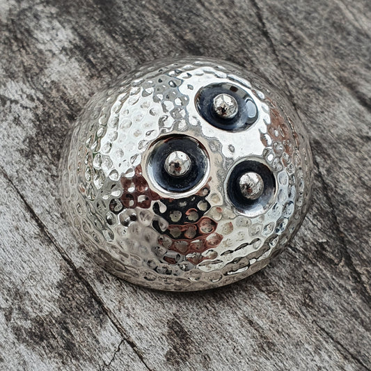 Metallic spherical object with three circular indentations containing small metal balls.