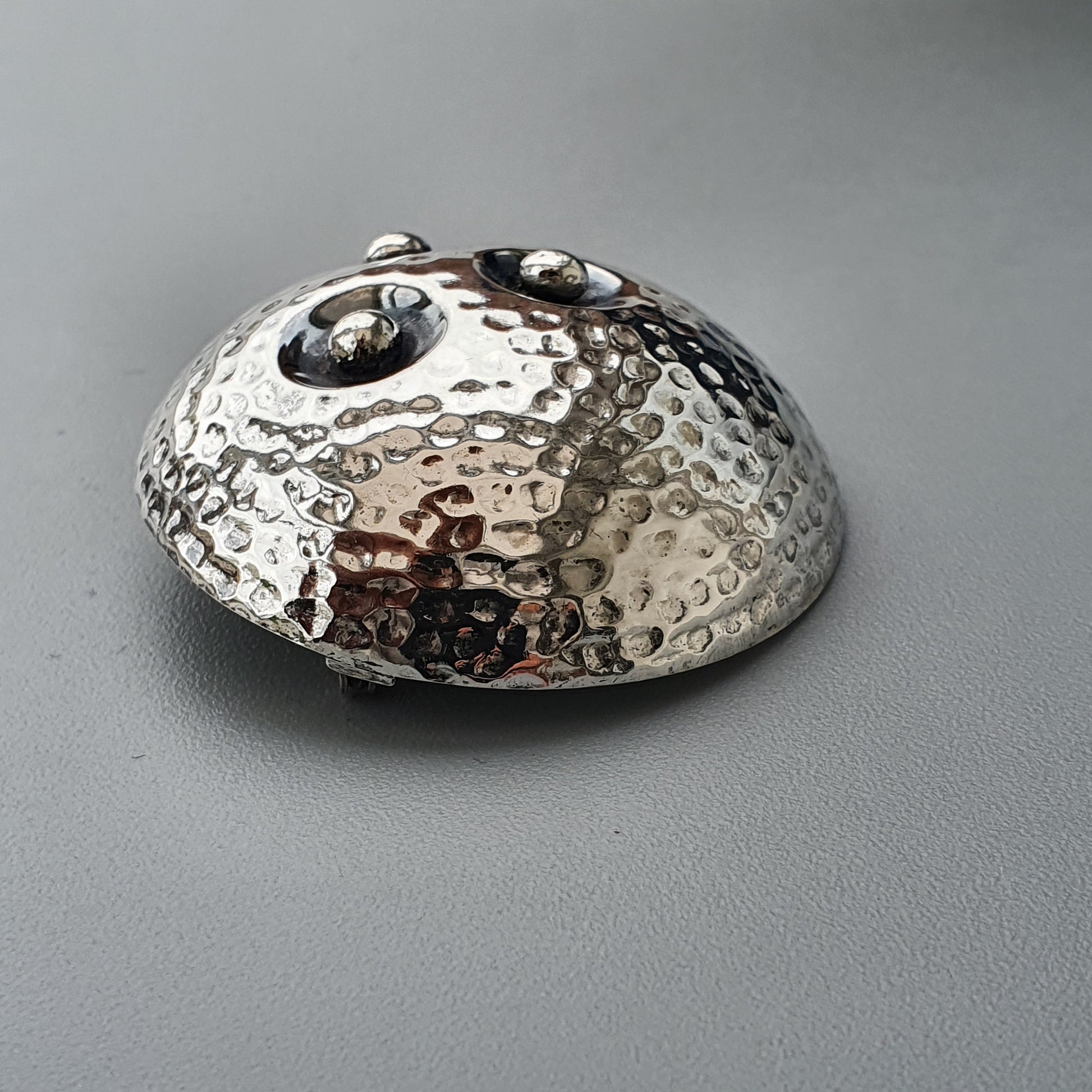 Hammered metal dome or hemisphere with a textured, dimpled surface.