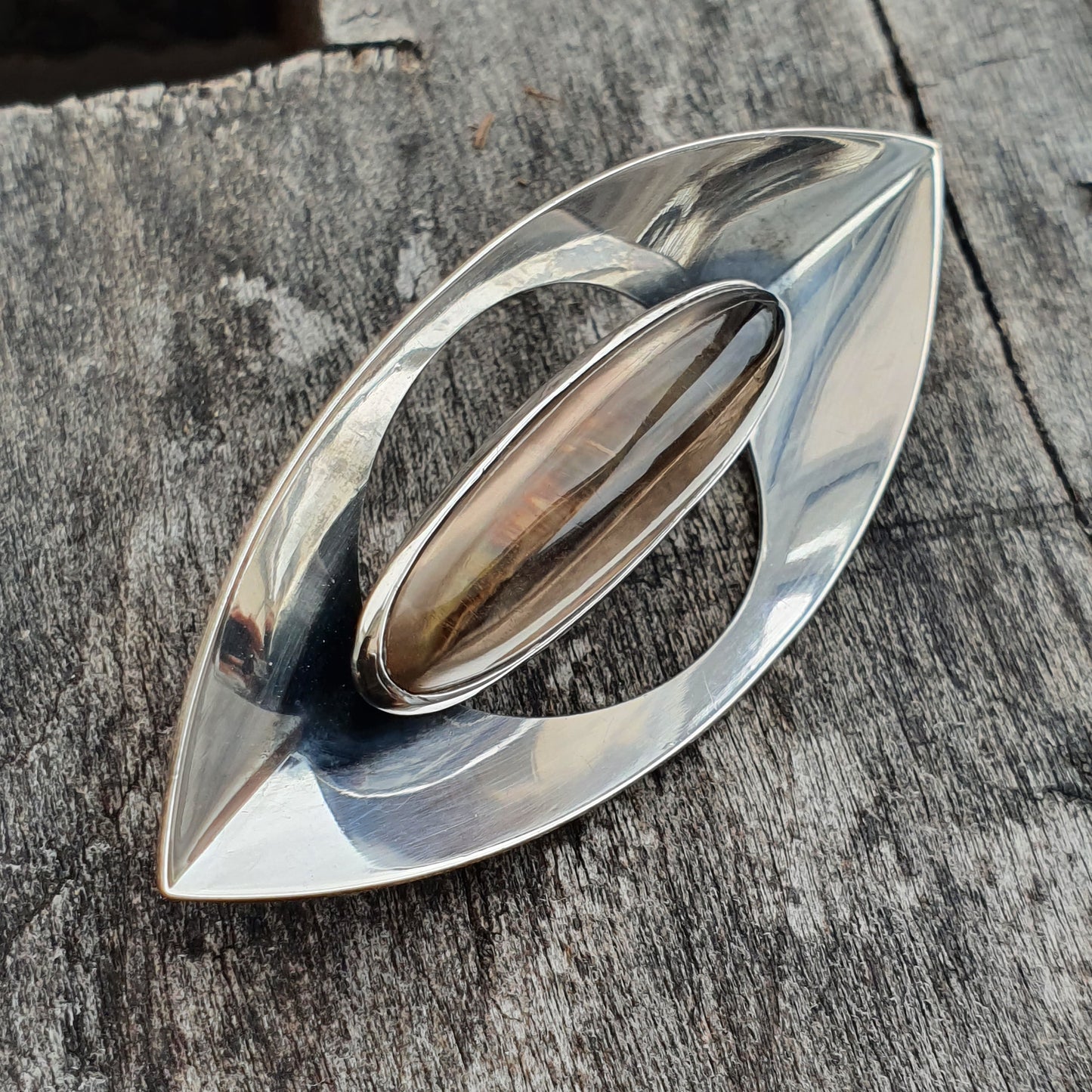 Sleek, eye-shaped silver brooch or pendant with an oval center.