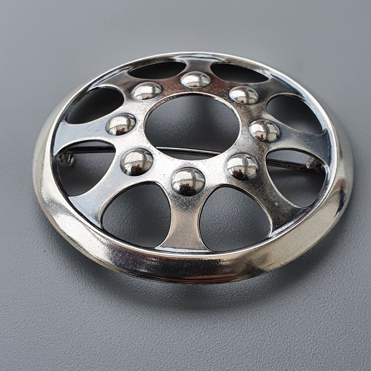 Metallic wheel cover or hubcap with circular cutouts and decorative spherical studs.