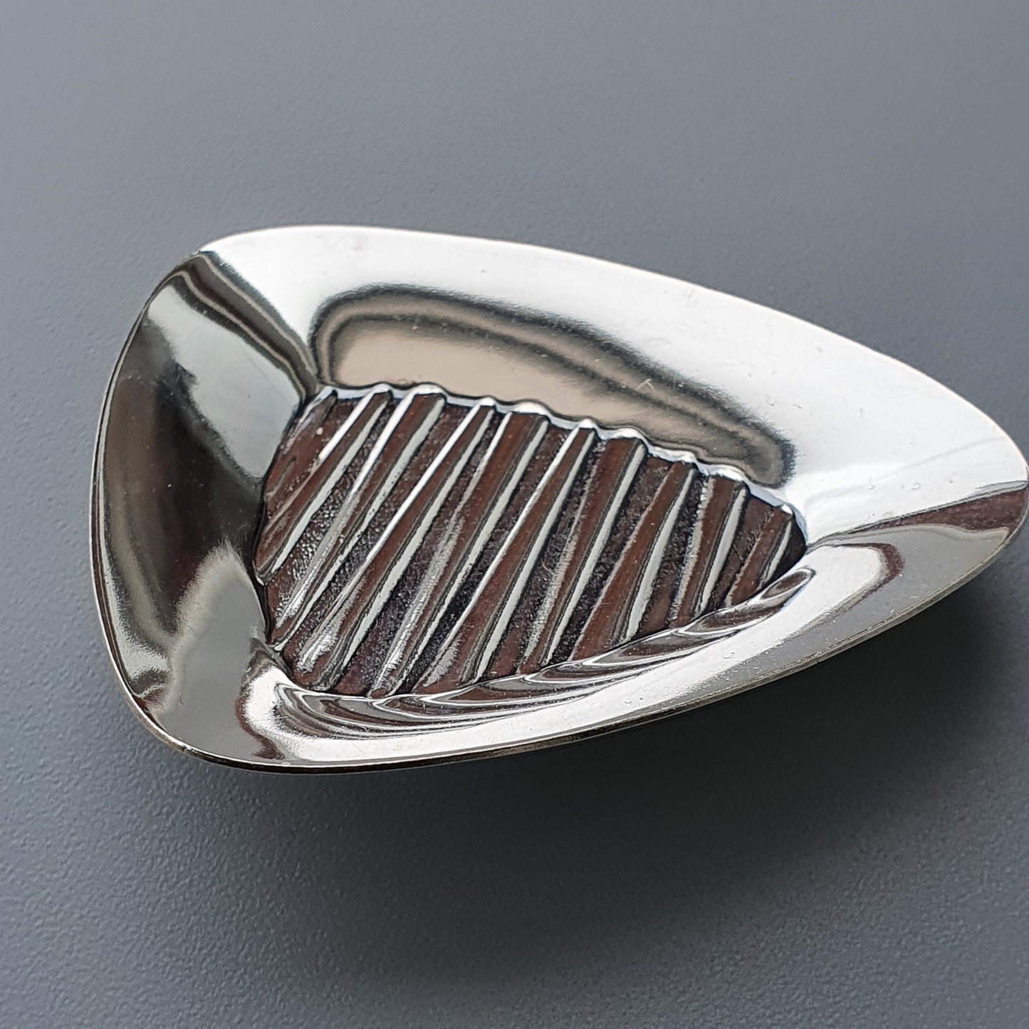 Shiny metal golf club head with grooved face.