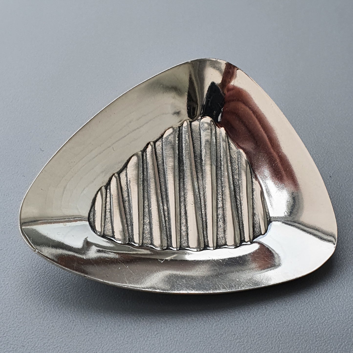 Triangular metallic ashtray with ridged center design.