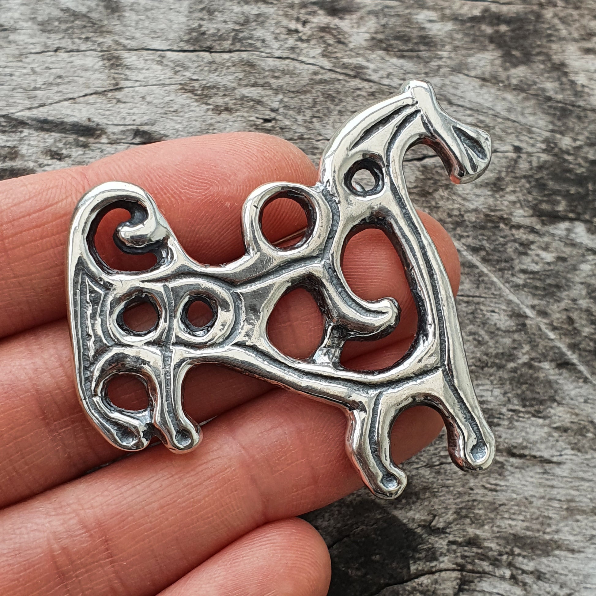 Ornate silver pendant shaped like a stylized horse or equine figure with Celtic-inspired swirls and openwork design.