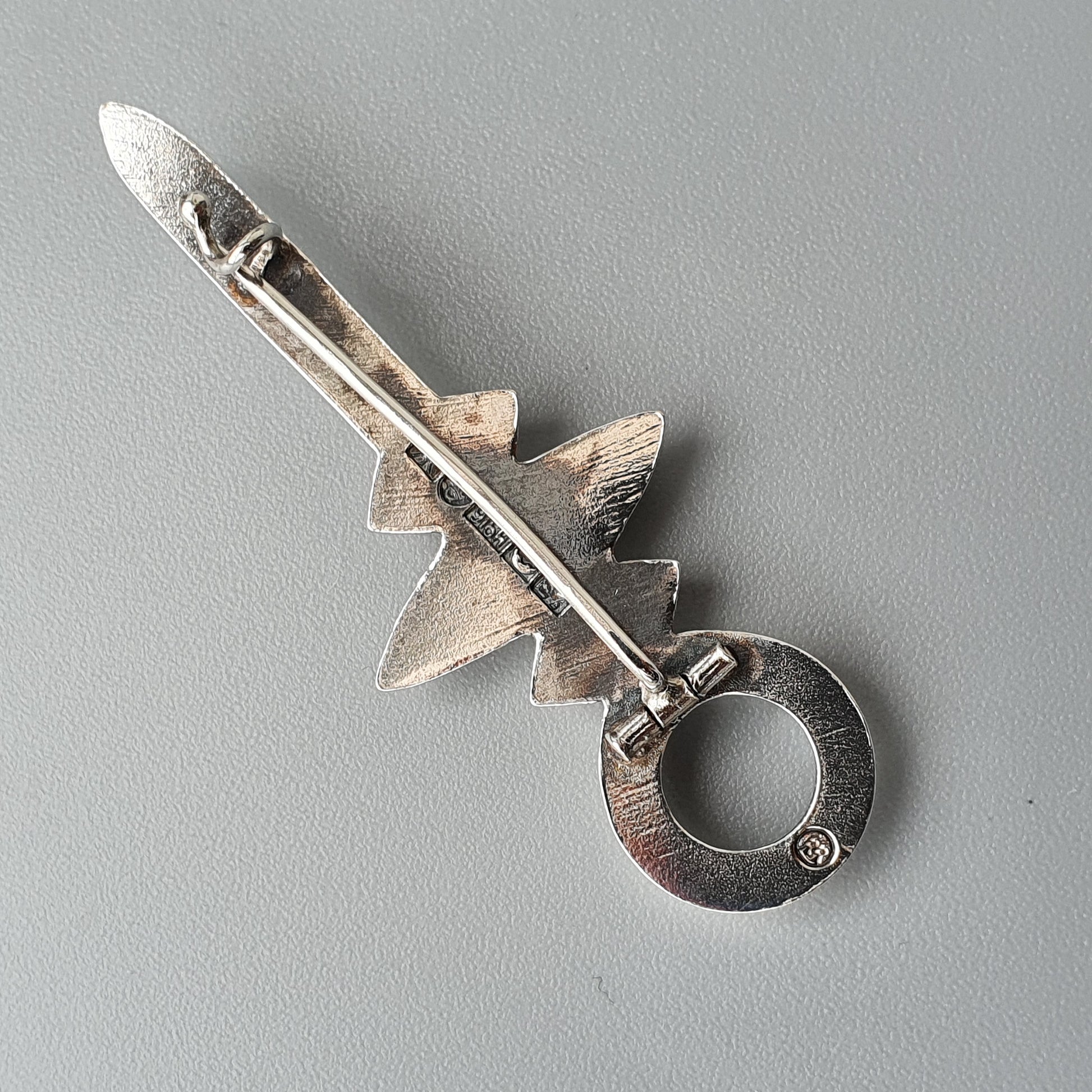 Silver viking style sword-shaped brooch with a ring at the base.