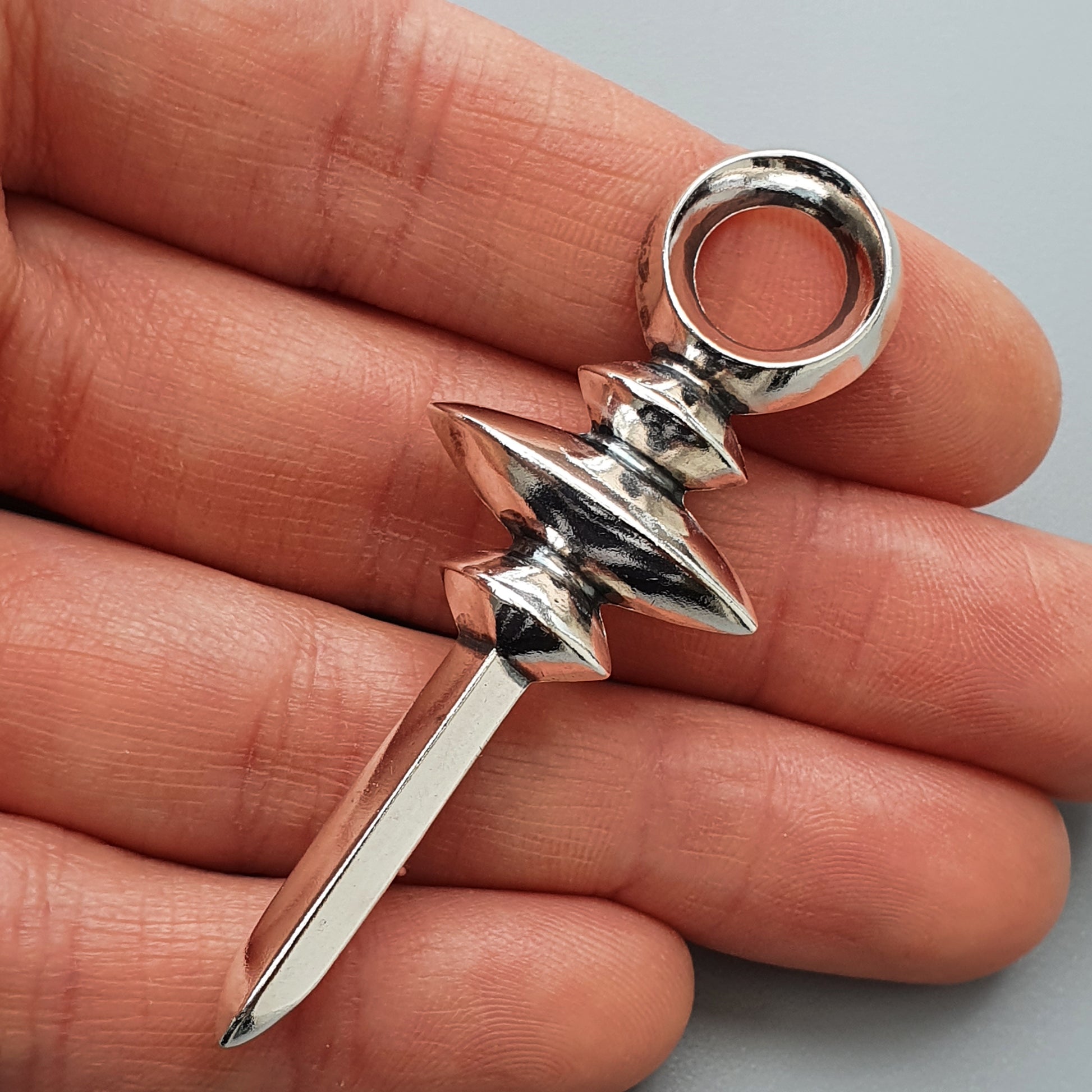 Silver brooch with a pointed spike and decorative beads or discs along its length.