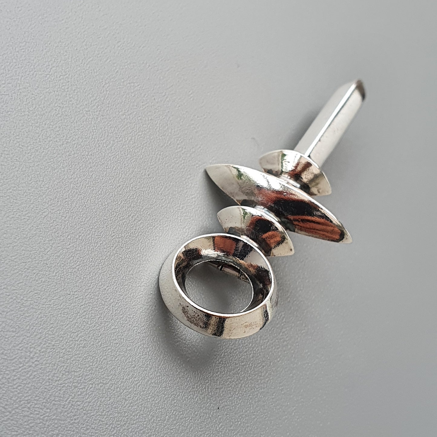 Silver ring-shaped bottle opener with a decorative pointed end.