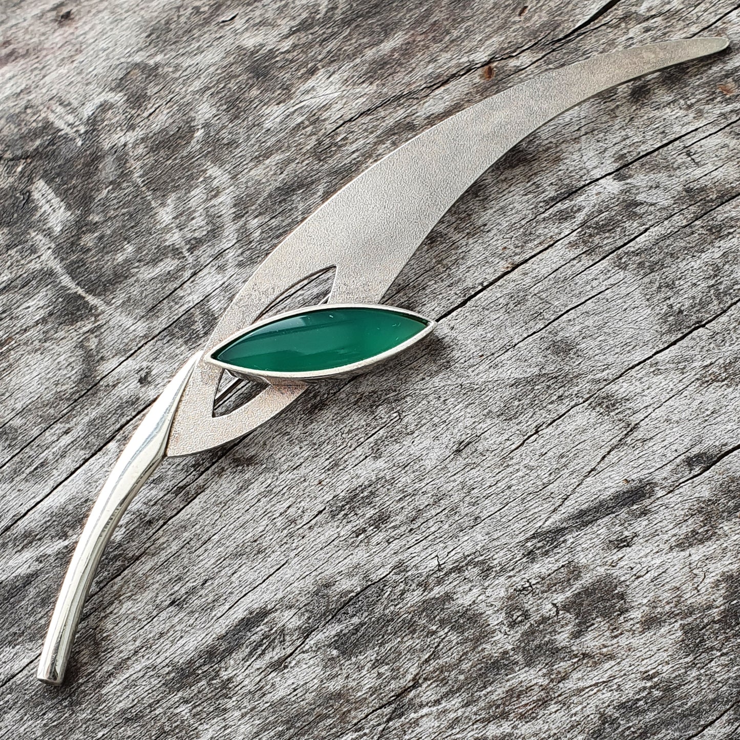 Silver brooch or pendant with a leaf-shaped green gemstone.