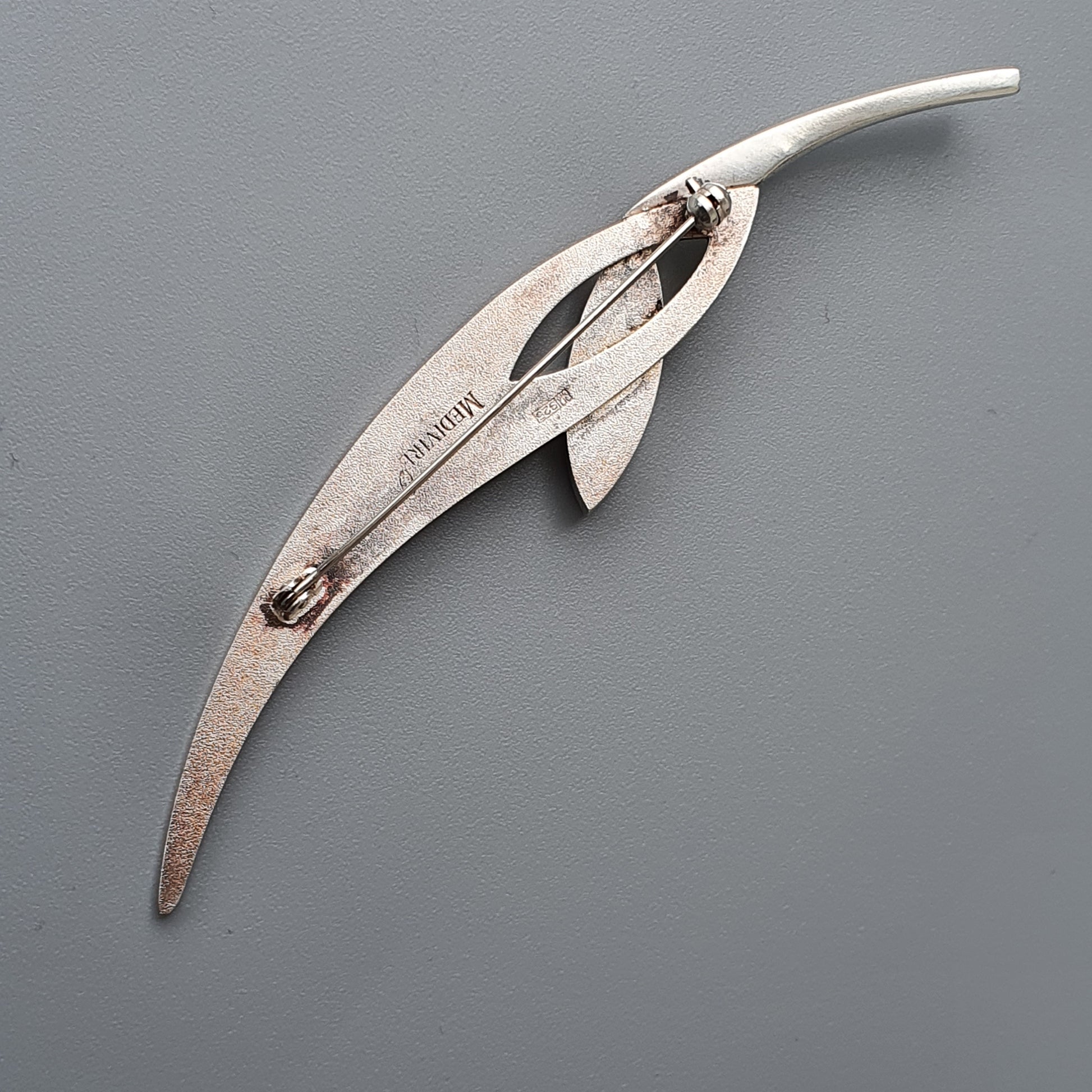 Curved metal tool resembling pliers or forceps with elongated handles.