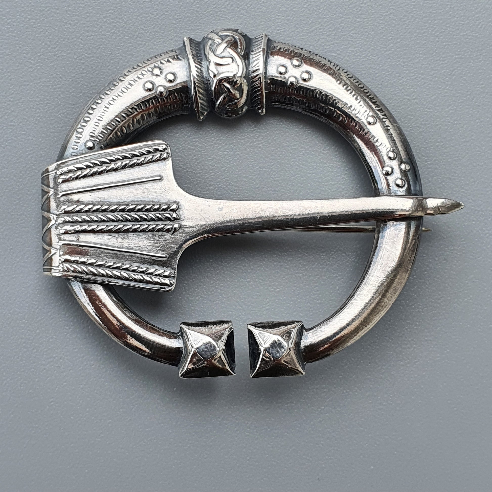 Ornate silver penannular brooch with intricate Celtic-style designs and a decorative pin.