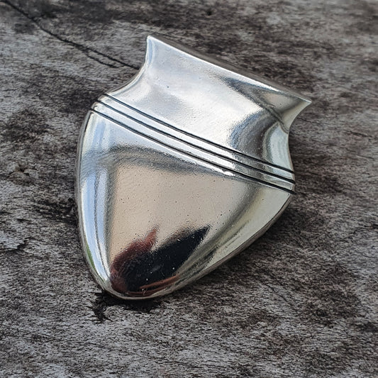 Shiny silver shield-shaped badge or emblem with horizontal stripes near the top.