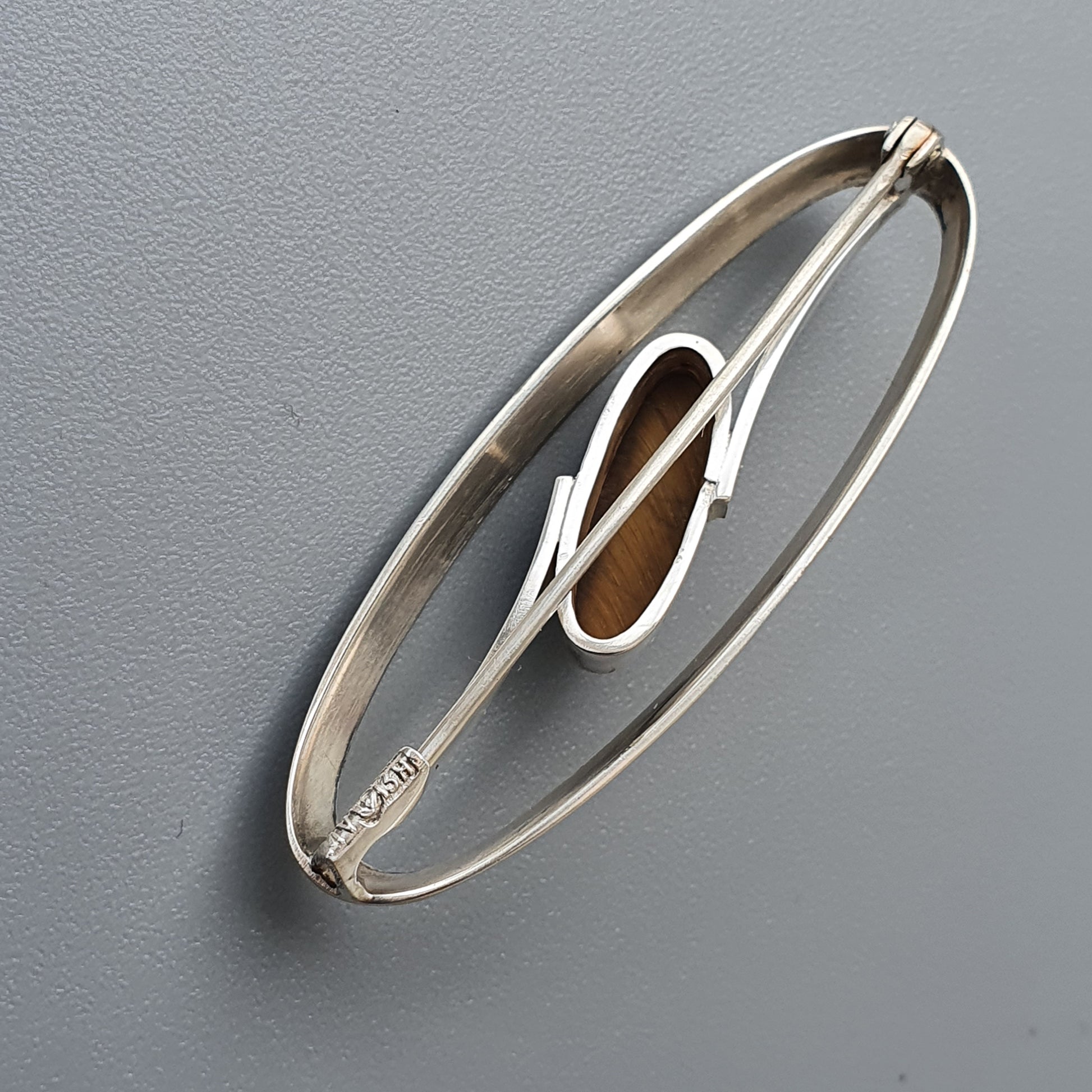 Oval-shaped silver brooch with an abstract geometric design in the center.