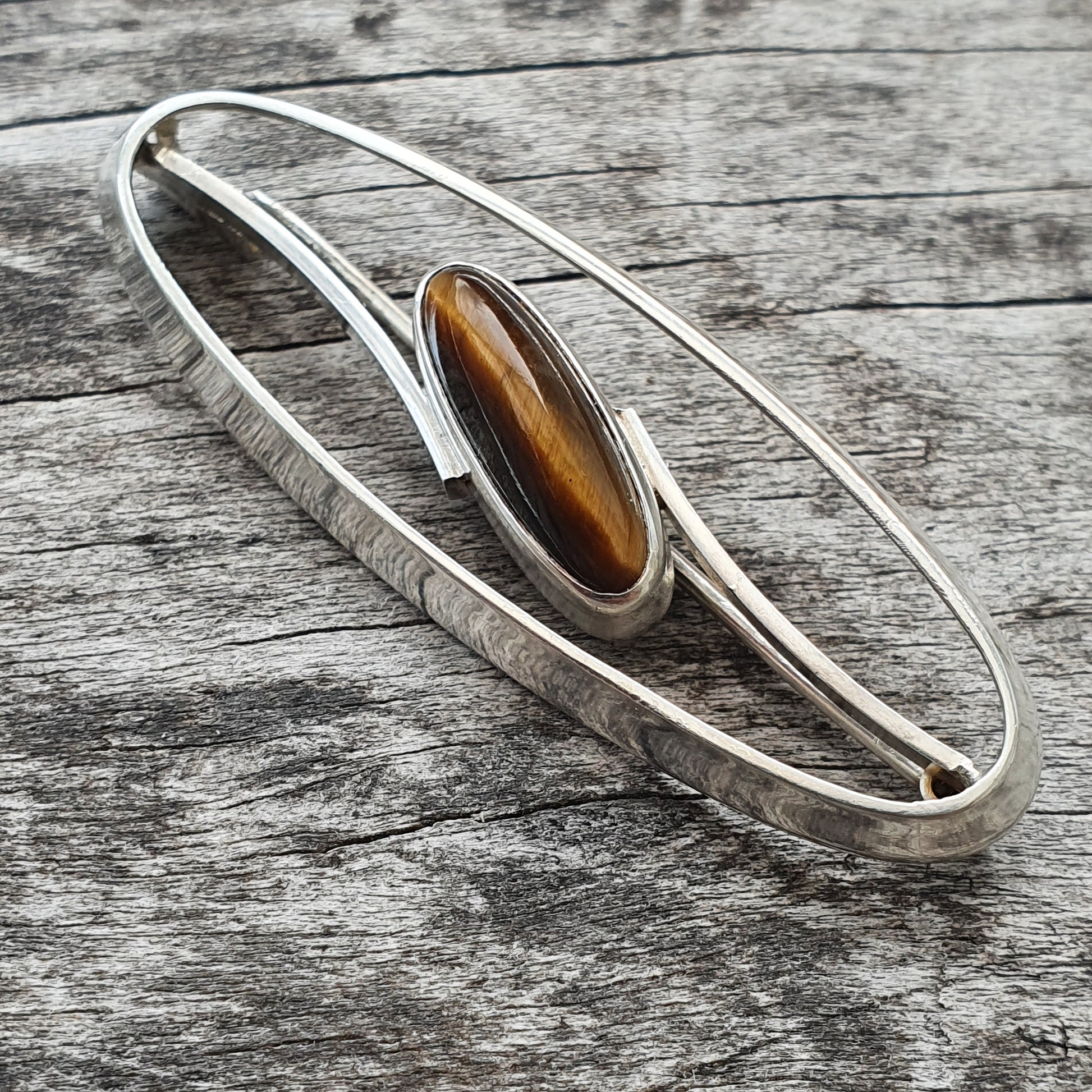 Silver bracelet with an oval tiger’s eye gemstone centerpiece.