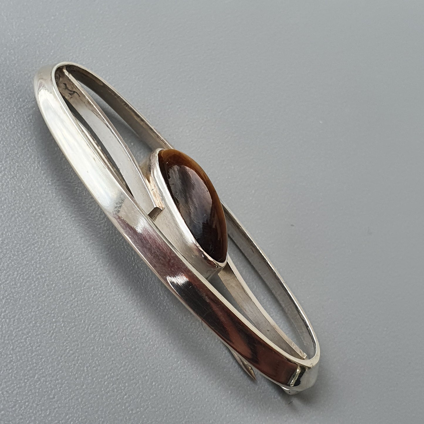 Silver bracelet with an oval brown stone or gem inset.