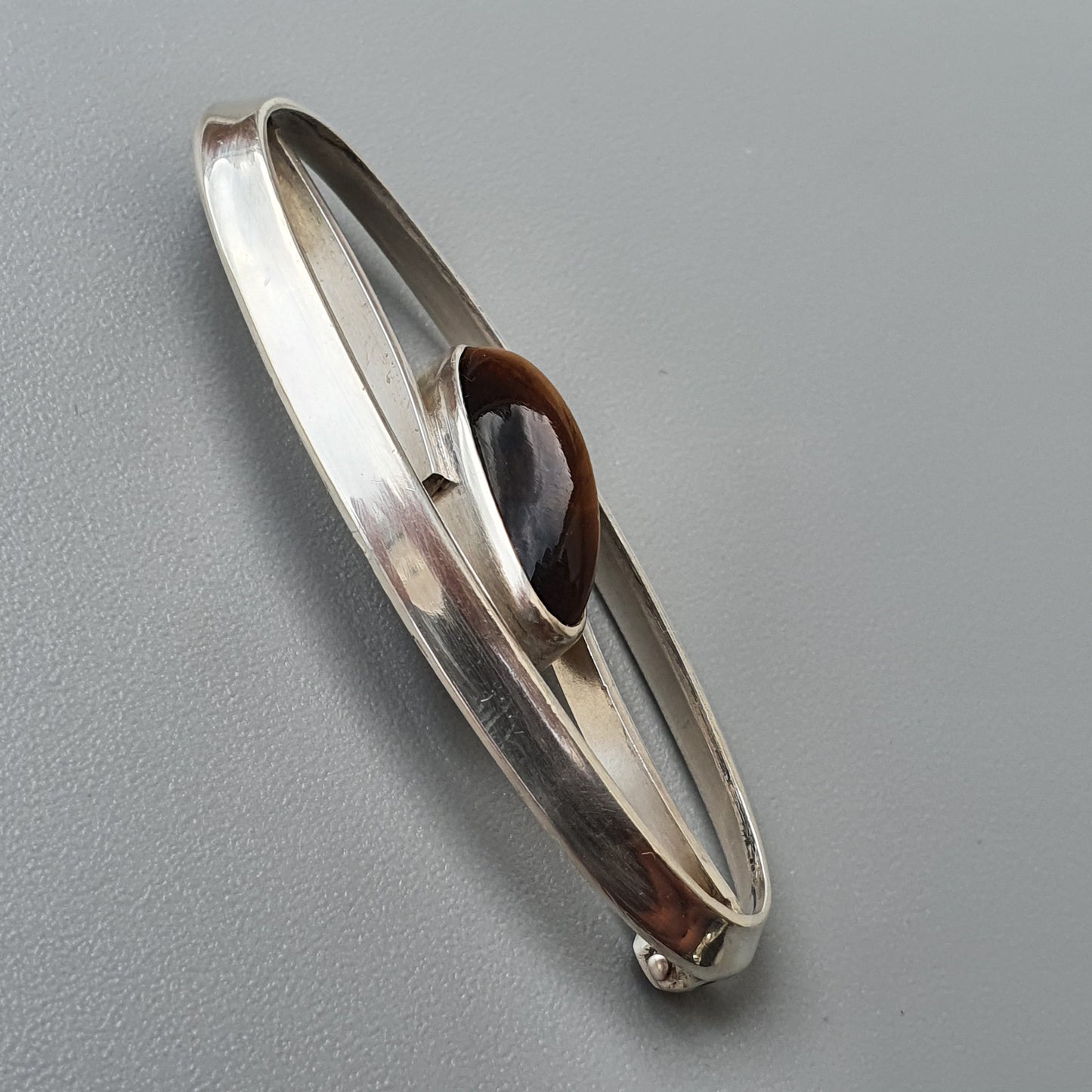 Silver bangle bracelet with a brown stone or gem inset.