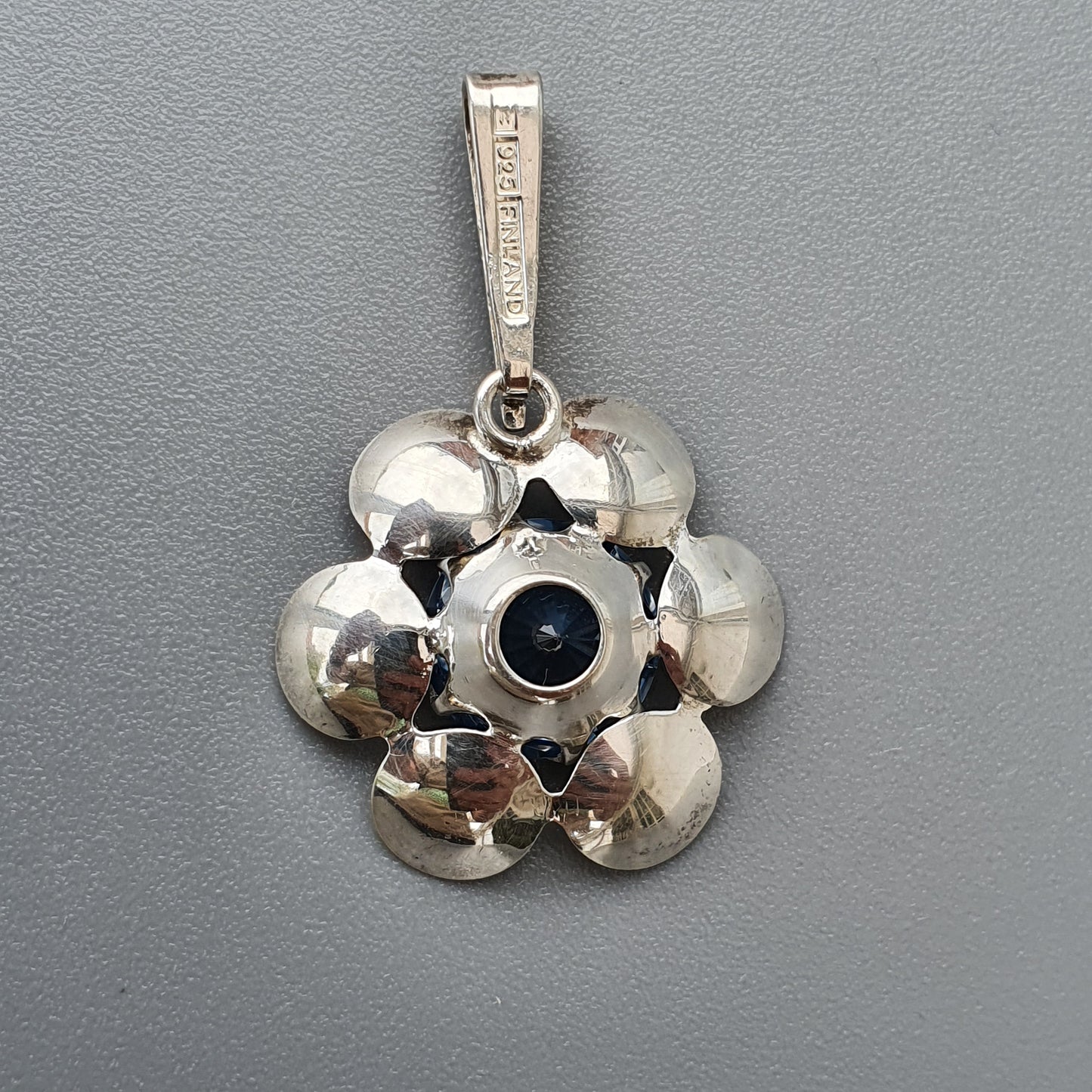 Silver flower-shaped pendant with a dark center stone.