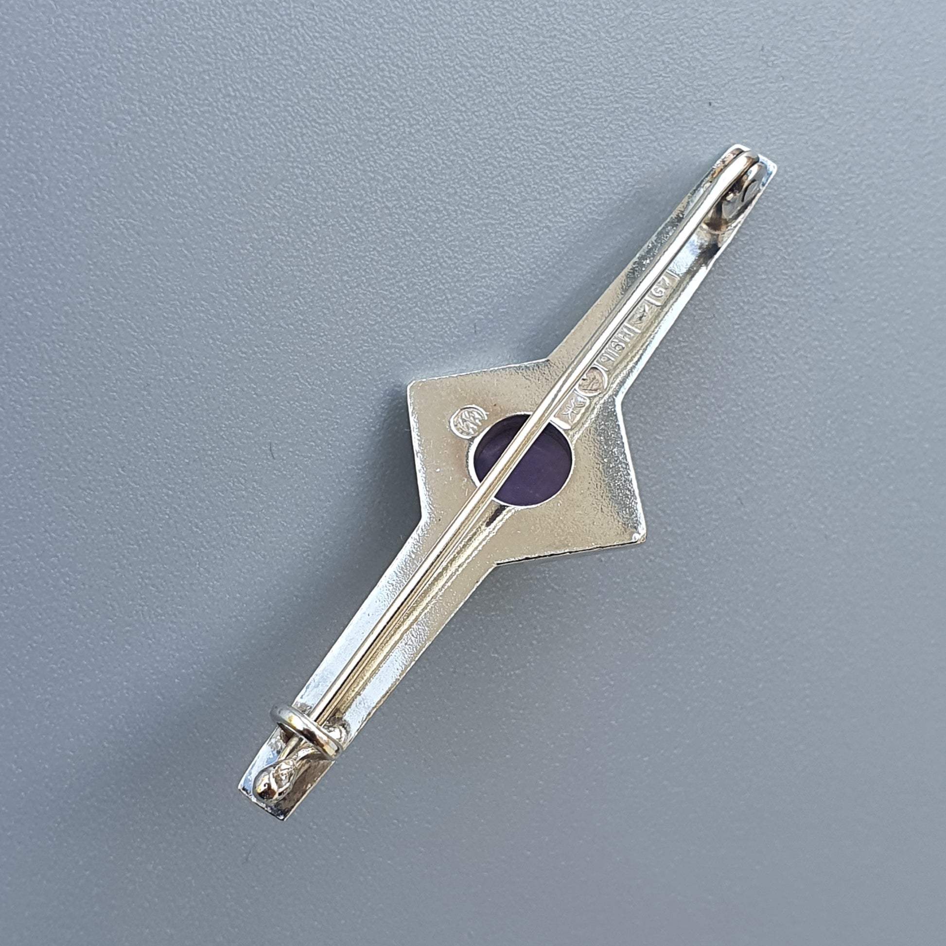 Metal compass tool with a diamond-shaped center and adjustable arms.