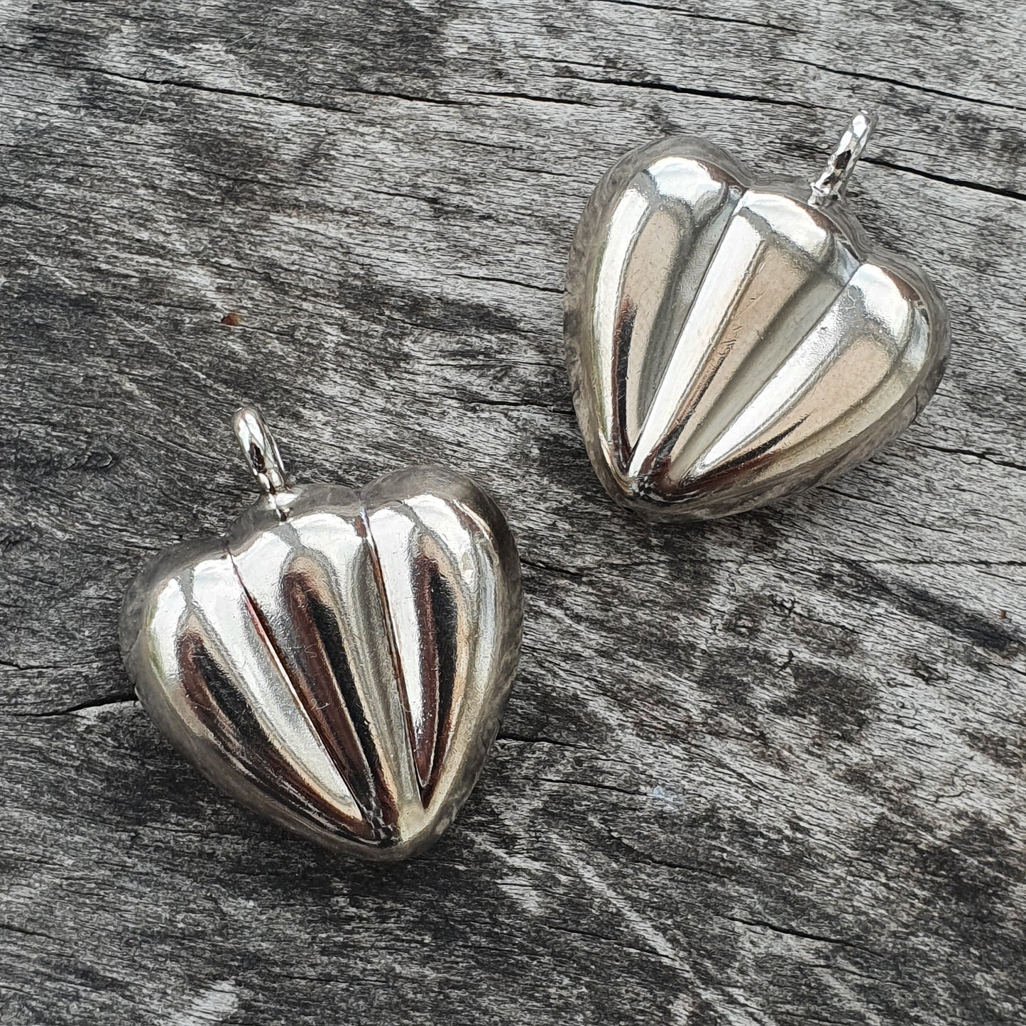 Silver heart-shaped pendants with ribbed designs.