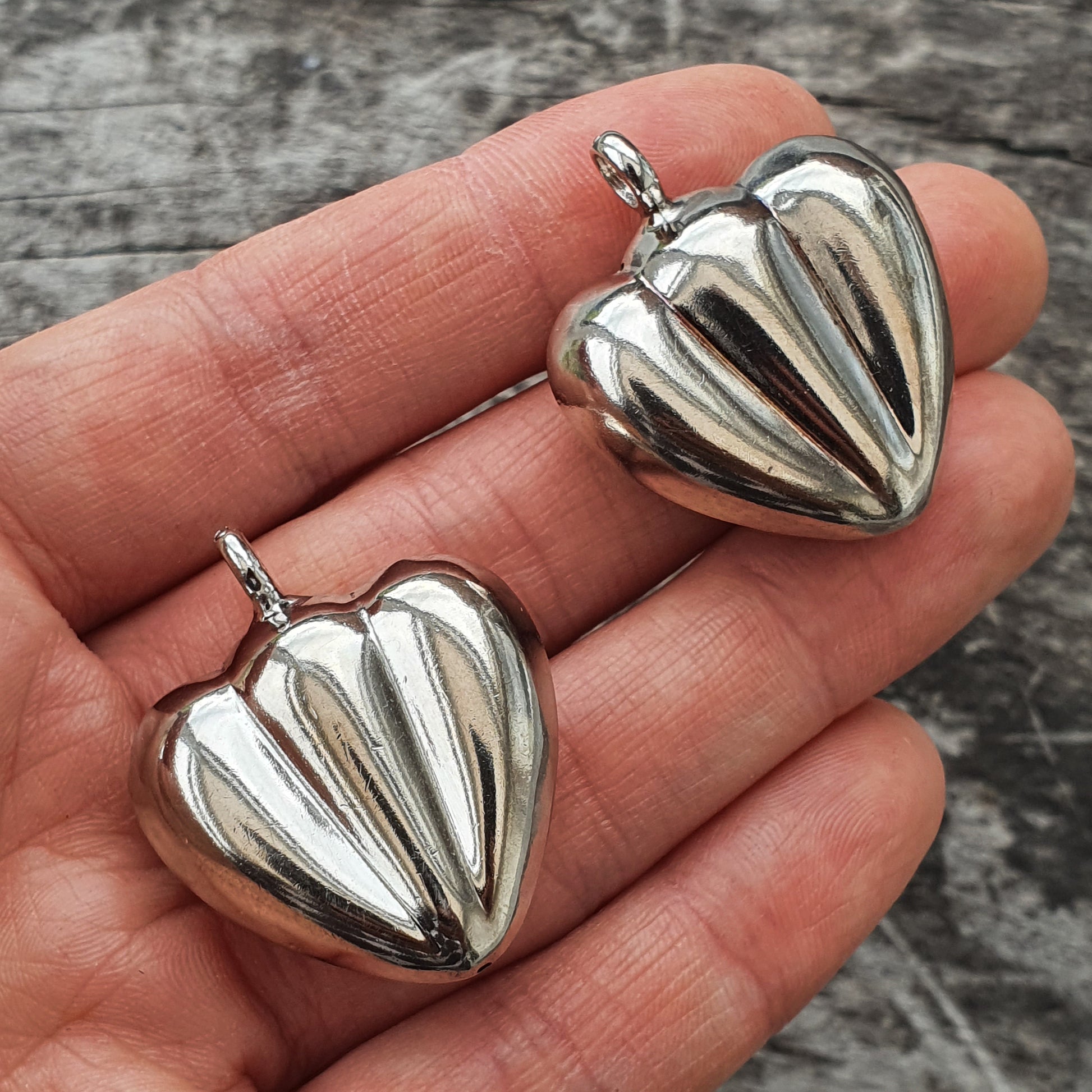 Silver heart-shaped pendants with ribbed designs.