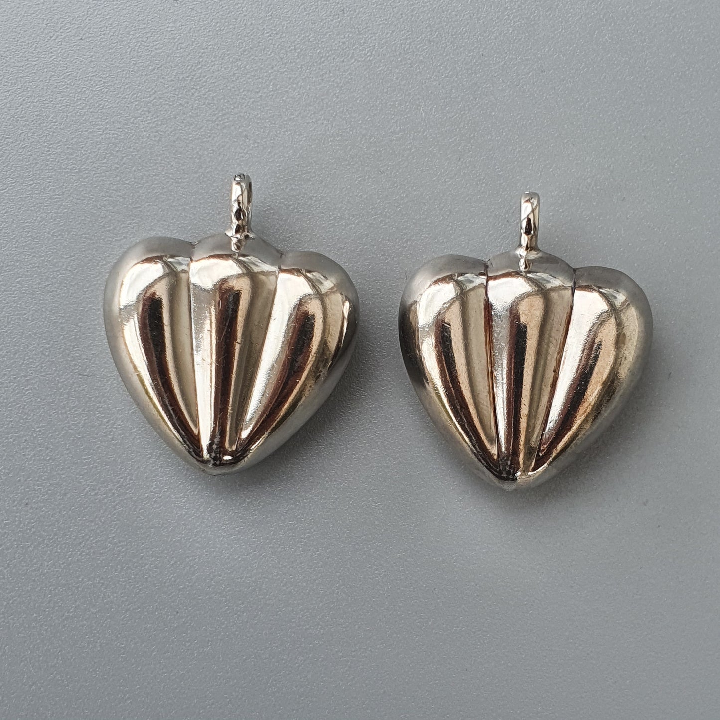 Two silver heart-shaped pendants with ribbed designs.