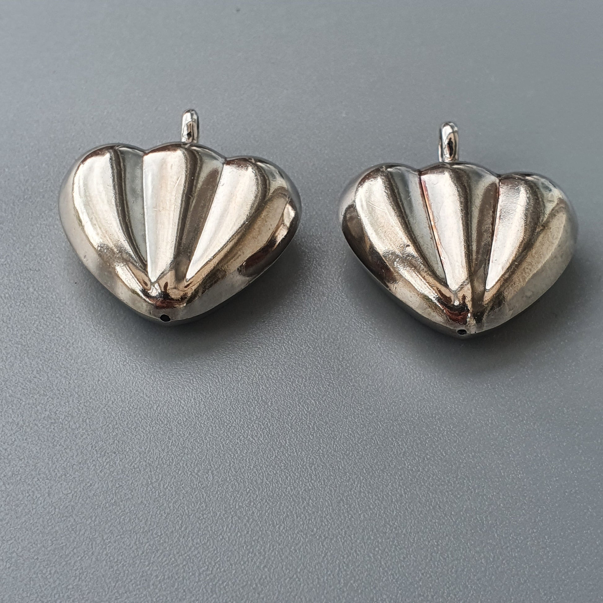 Two silver heart-shaped pendants with ribbed surfaces.