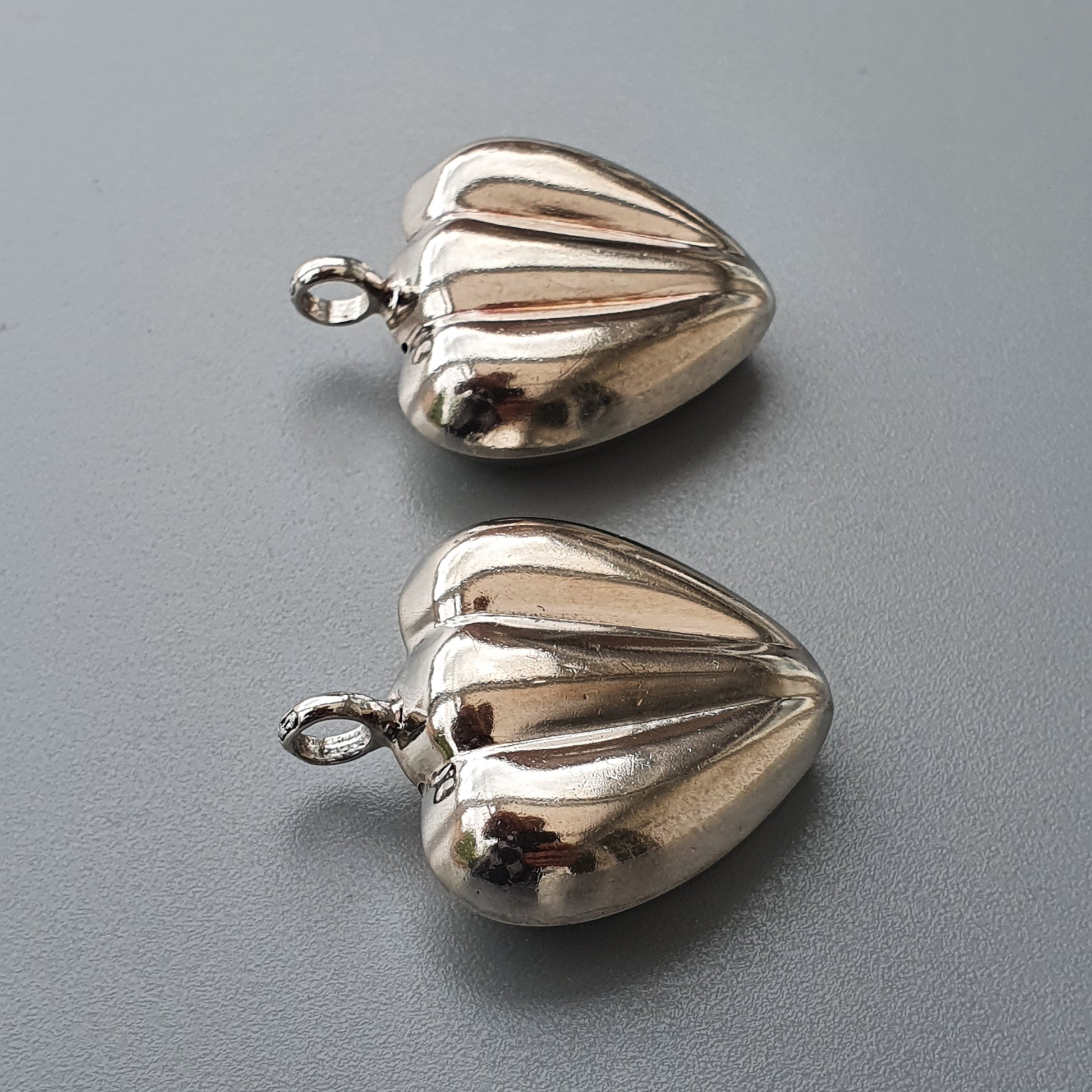 Silver heart-shaped pendants with ribbed surfaces and small loops for attachment.