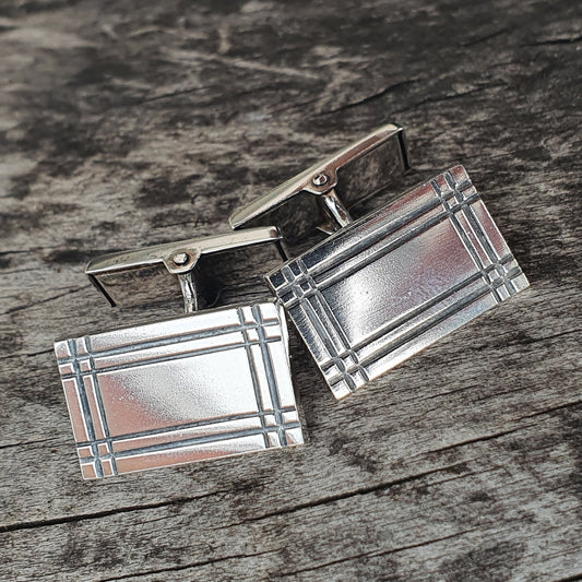 Pair of silver rectangular cufflinks with a geometric pattern.