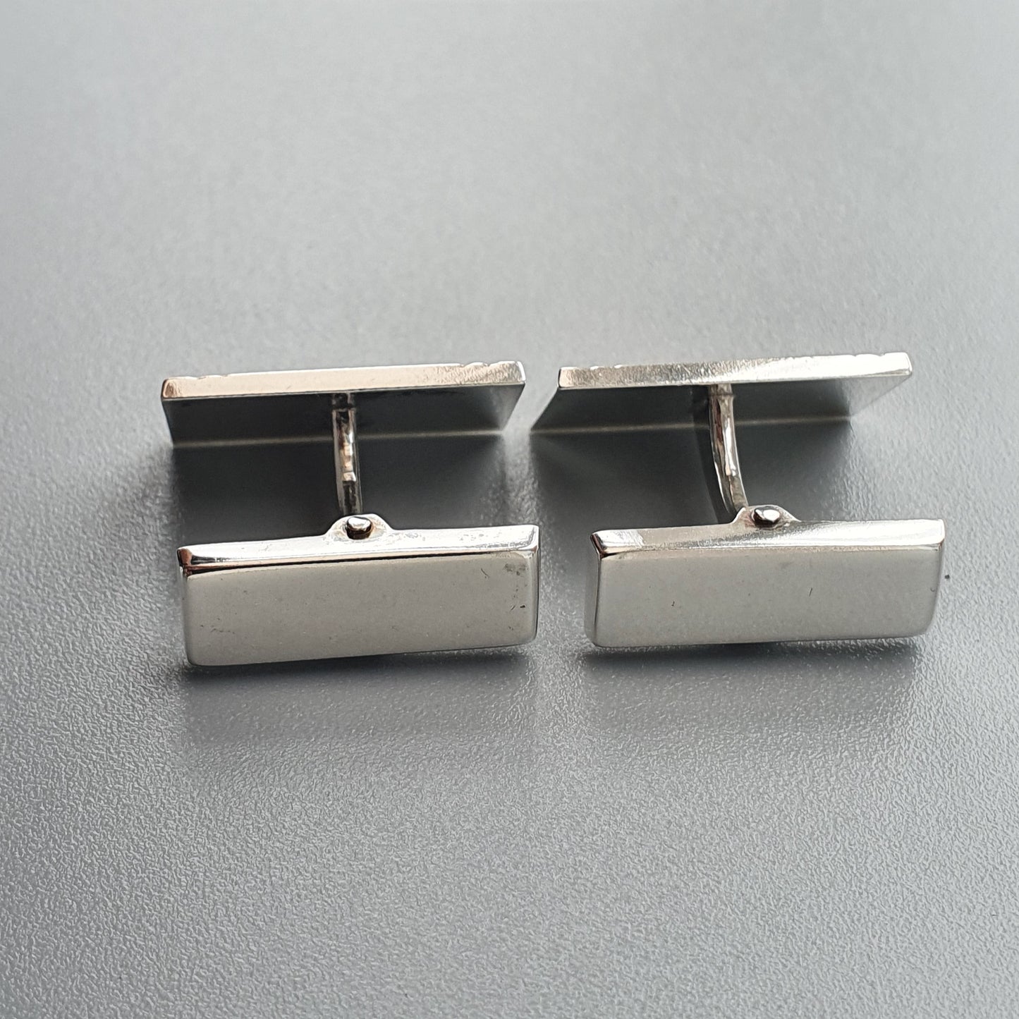 Pair of silver rectangular cufflinks with smooth surfaces.