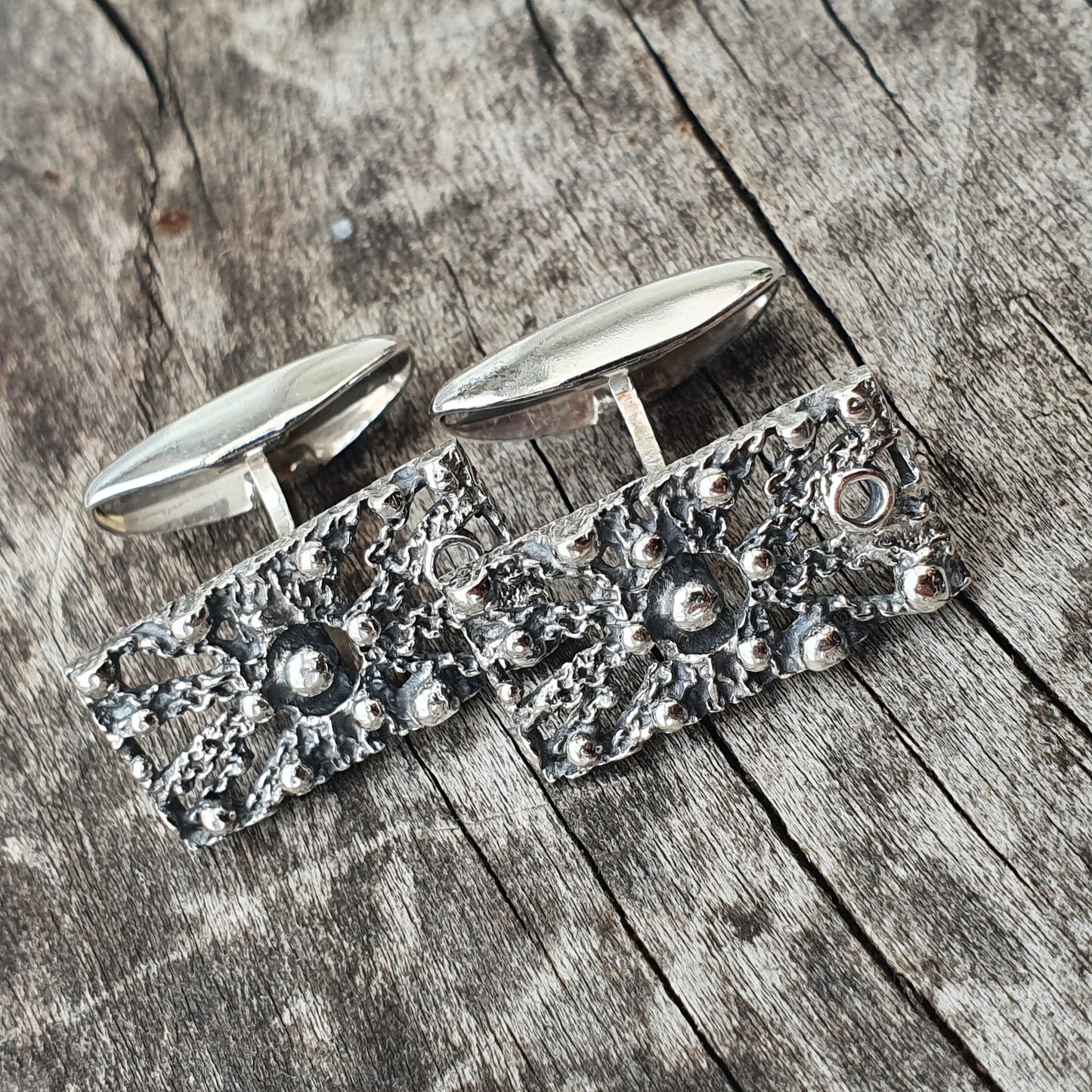 Pair of ornate silver cufflinks with textured, floral-patterned surfaces.