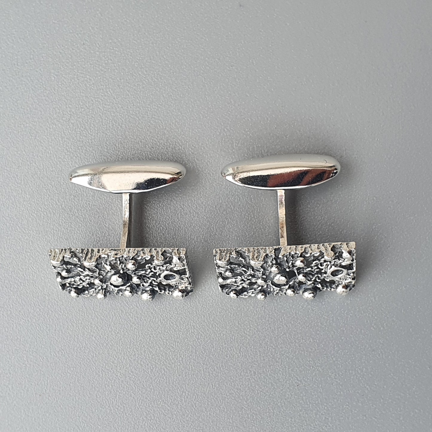 Pair of silver cufflinks with textured rectangular bases.