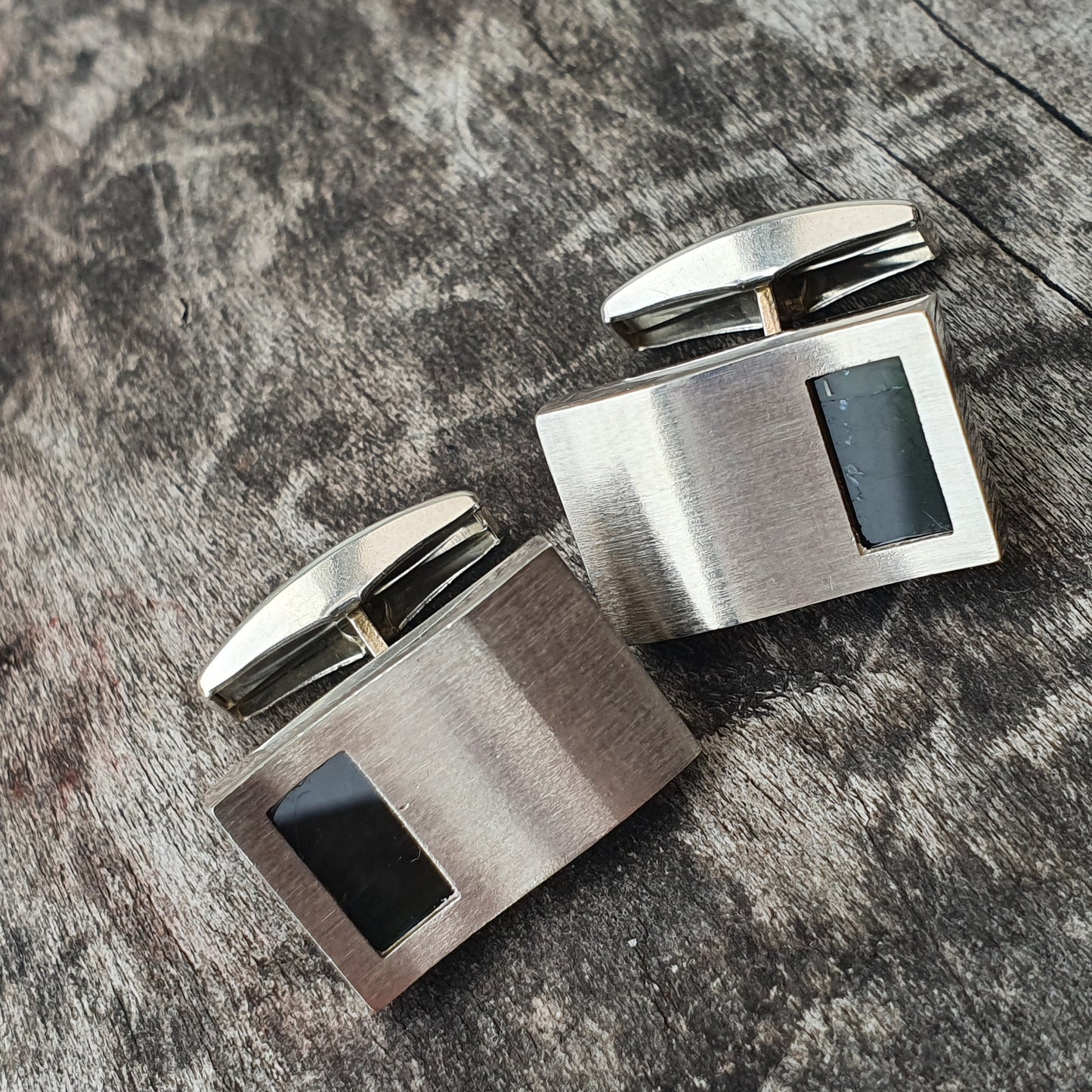 Pair of silver cufflinks with black inlay accents.