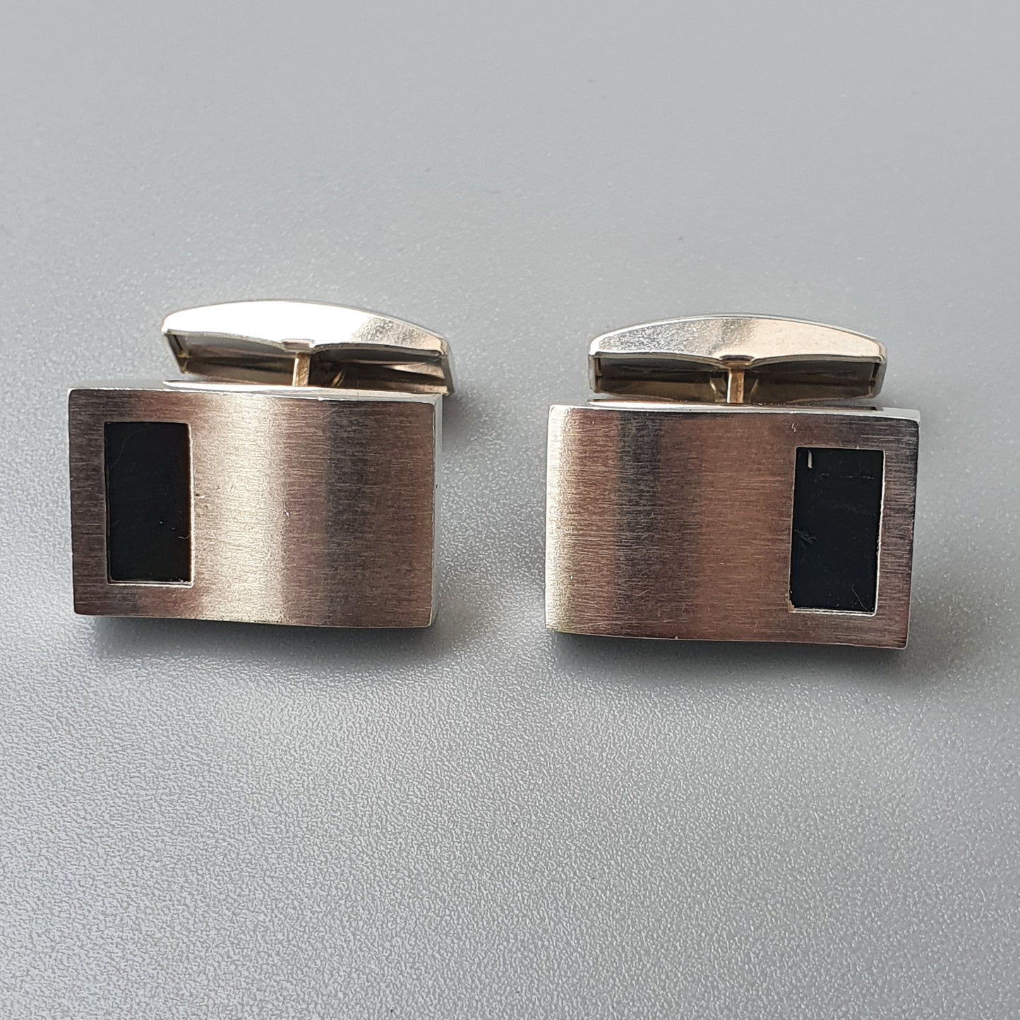 Pair of rectangular metal cufflinks with black inlay accents.