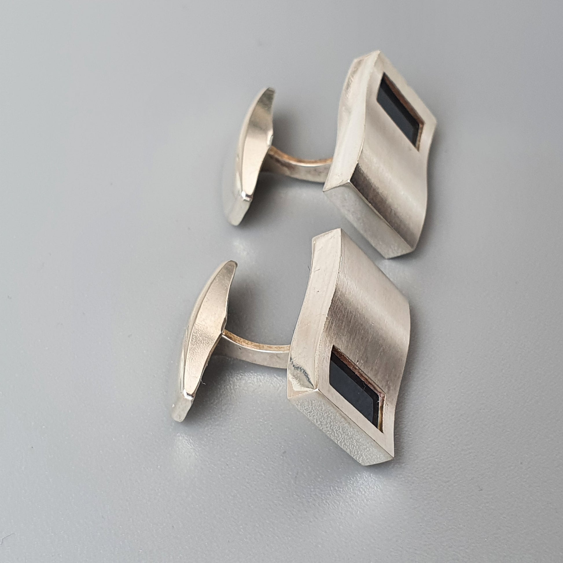 Pair of silver-toned rectangular cufflinks with dark inlays.