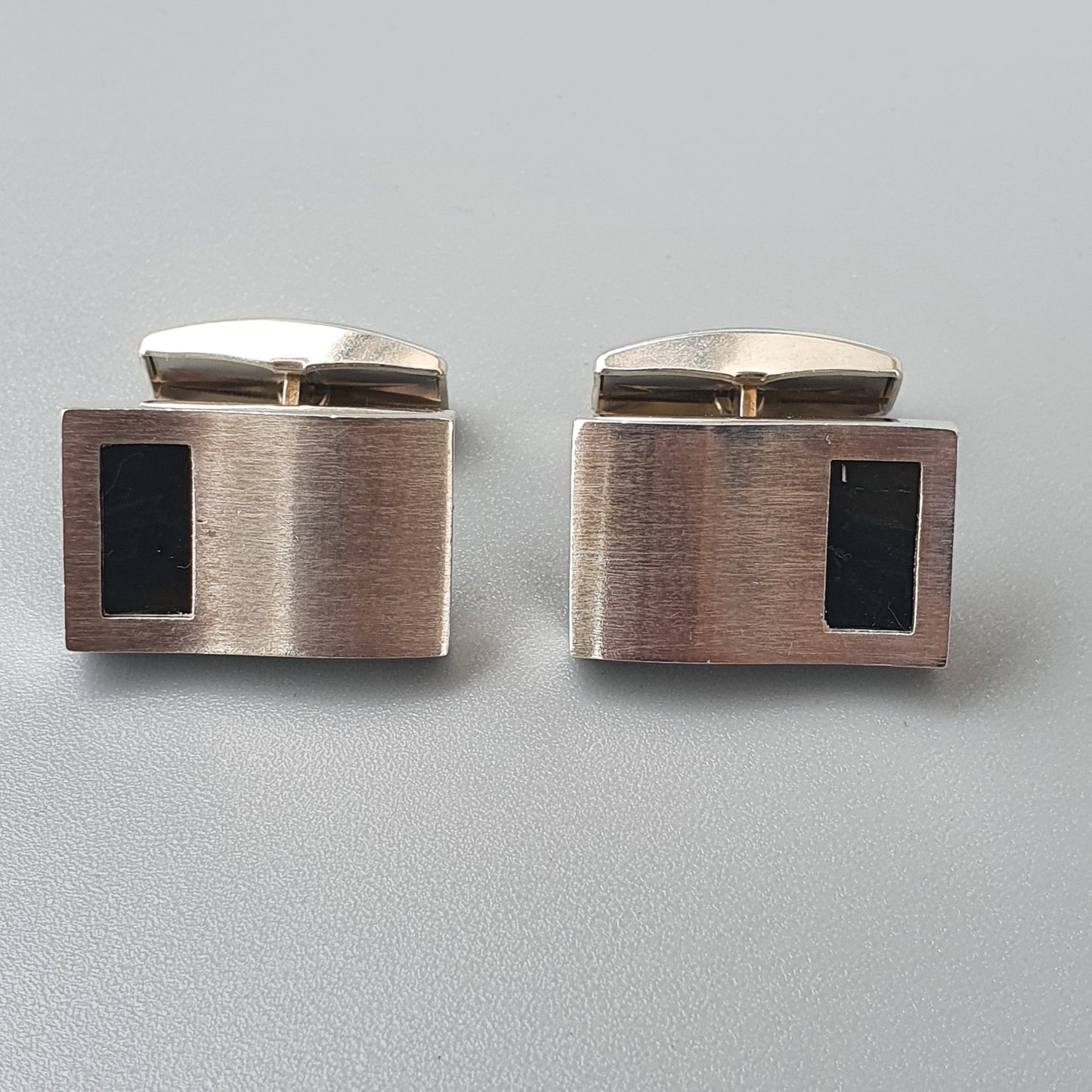 Pair of rectangular metal cufflinks with black inlays.