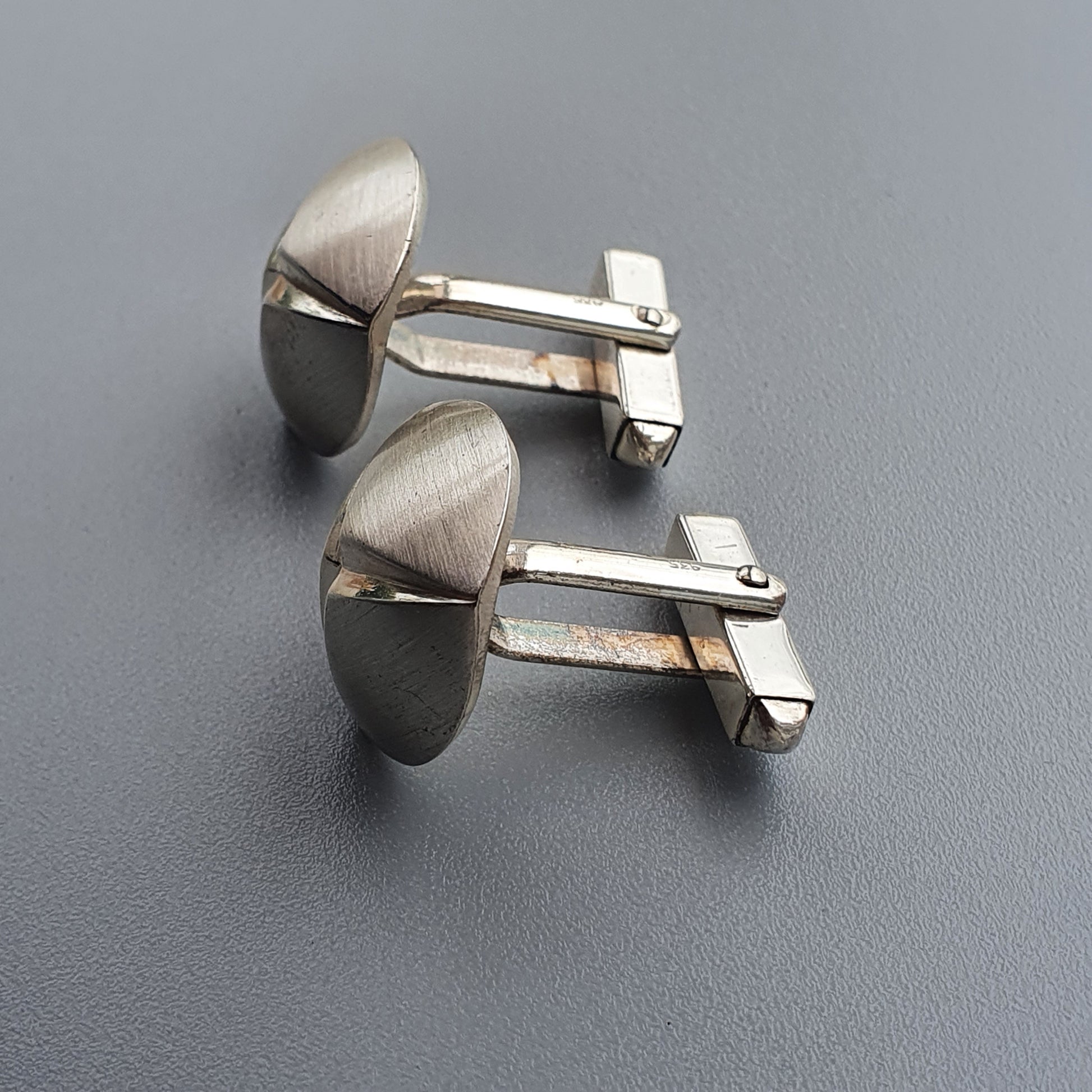 Pair of silver cufflinks with curved, shield-like designs.